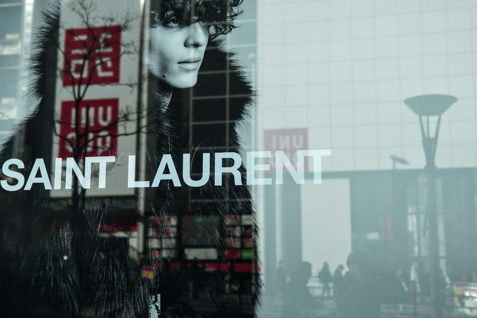 Riflessione di un modello nella vetrina di Saint Laurent con sfondo urbano