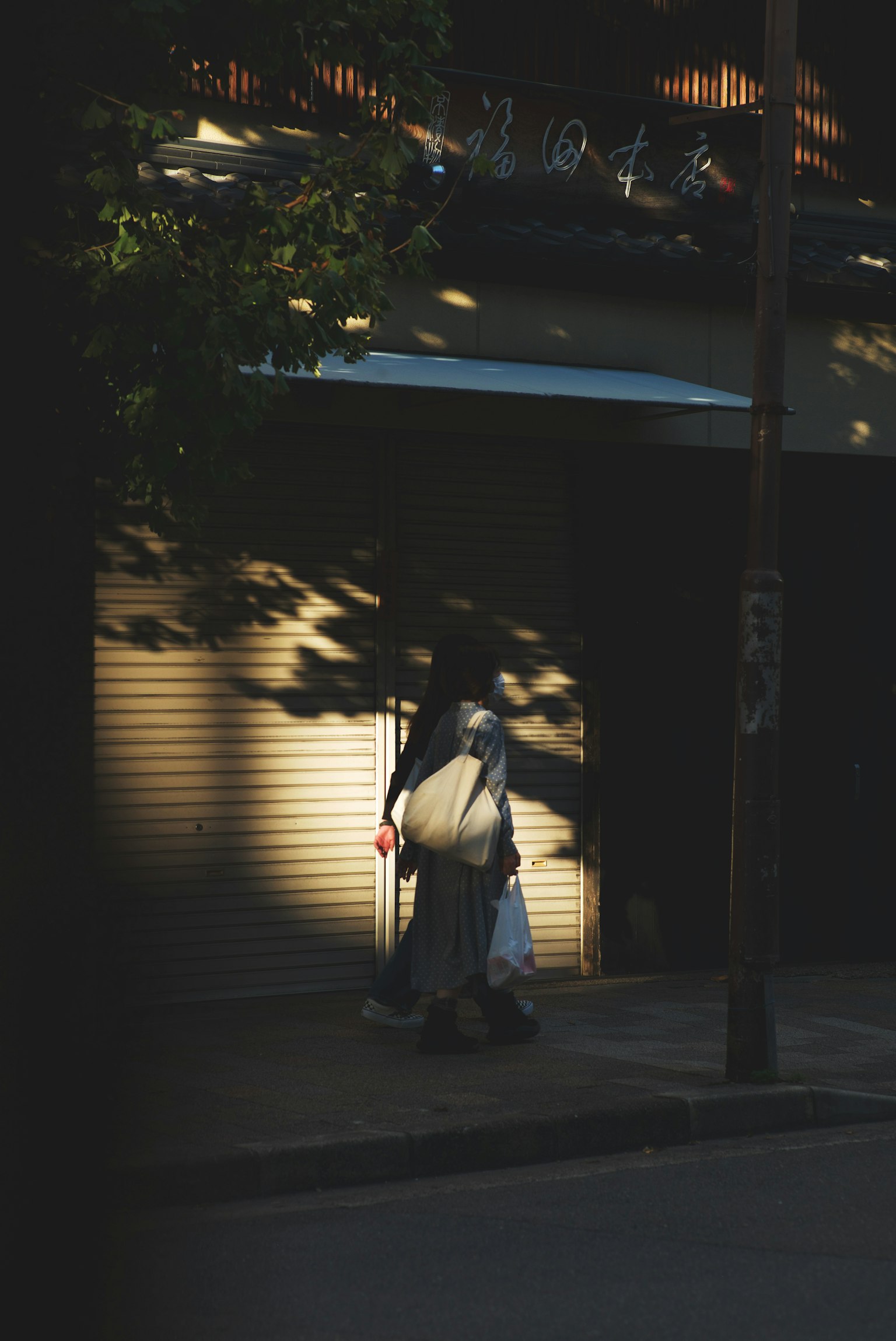 Una persona caminando por una calle tranquila con sombras