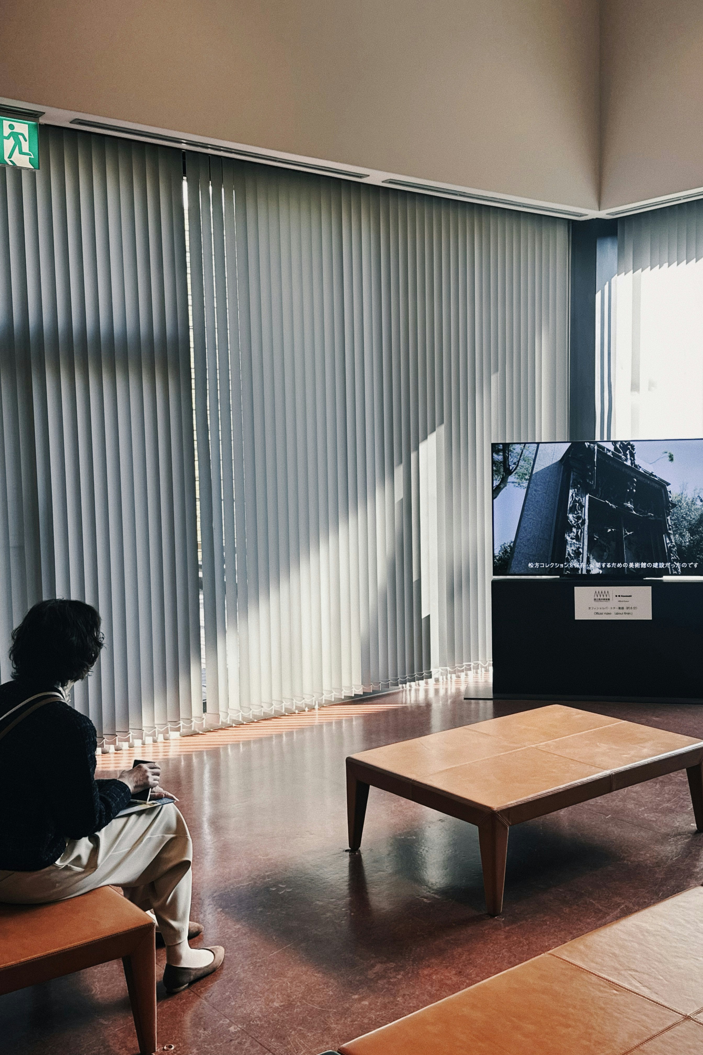 美術館の展示室でベンチに座る人物
