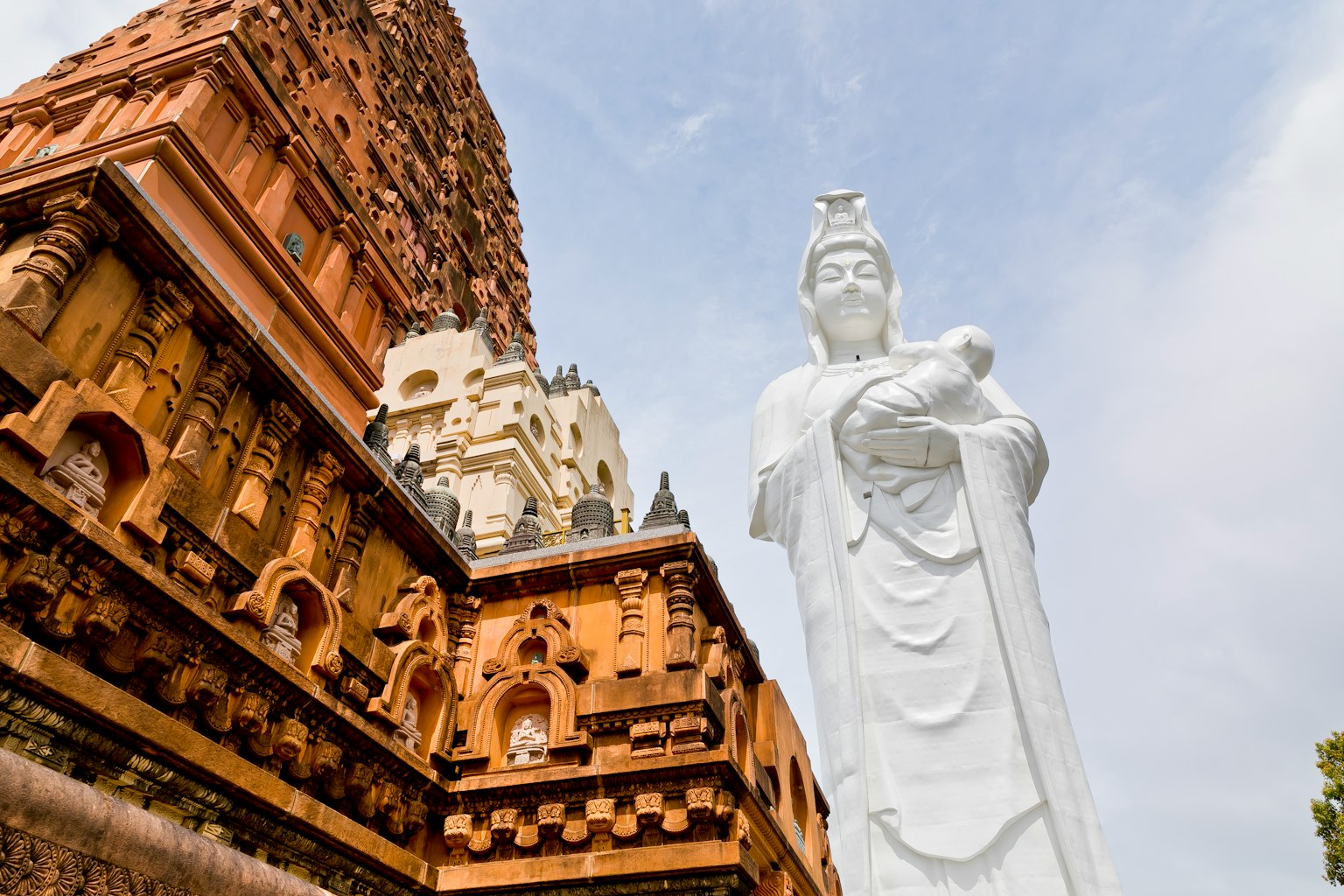 Una estatua blanca de Guanyin junto a la arquitectura de un templo antiguo