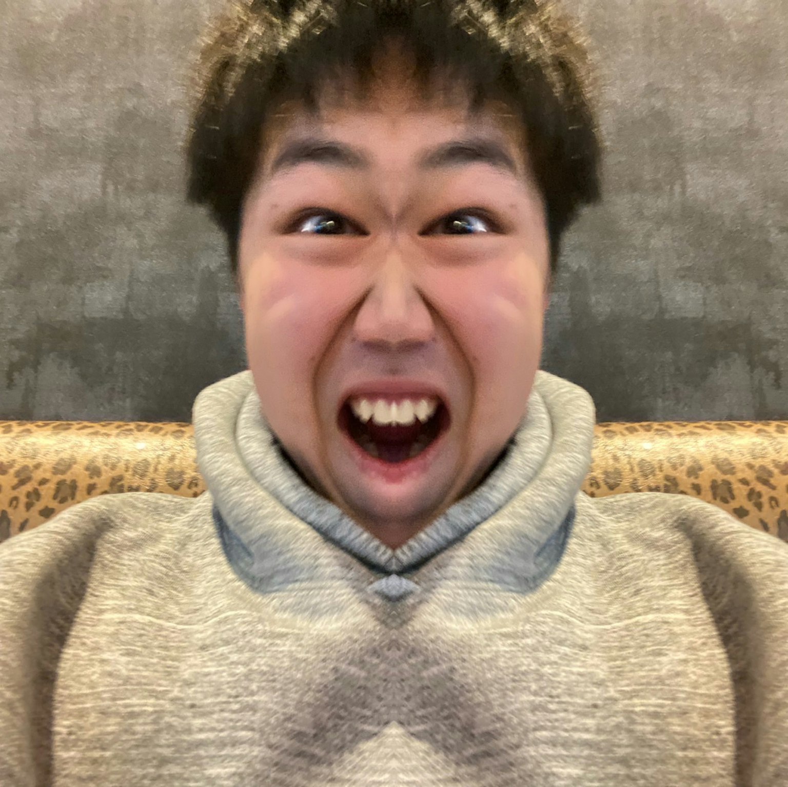 一位年輕男性露出驚訝的表情，穿著灰色連帽衫