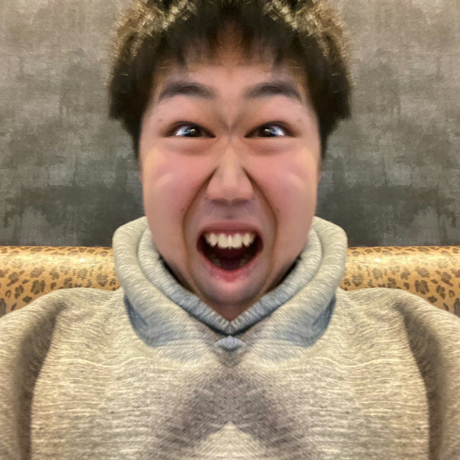 A young man with a surprised expression wearing a gray hoodie