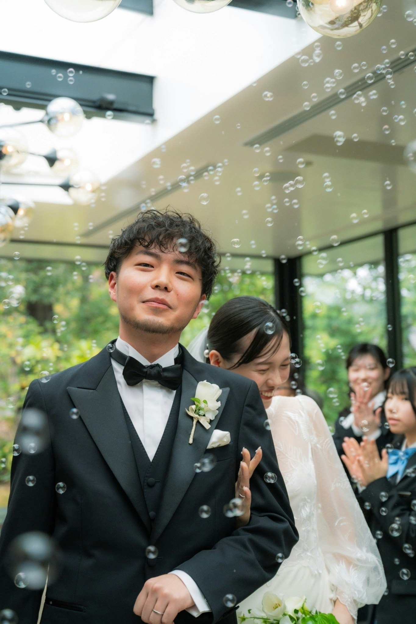 緑の庭で寄り添う新郎新婦と祝福のゲストの姿