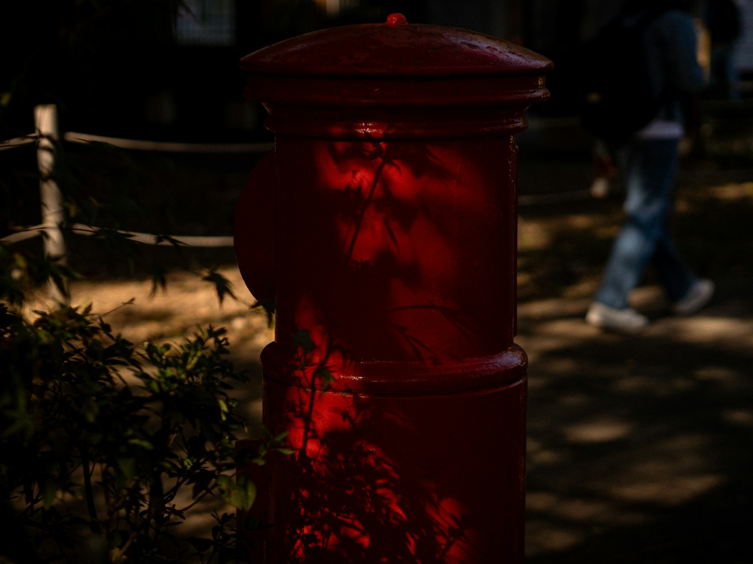 Boîte aux lettres rouge avec des ombres environnantes dans un parc