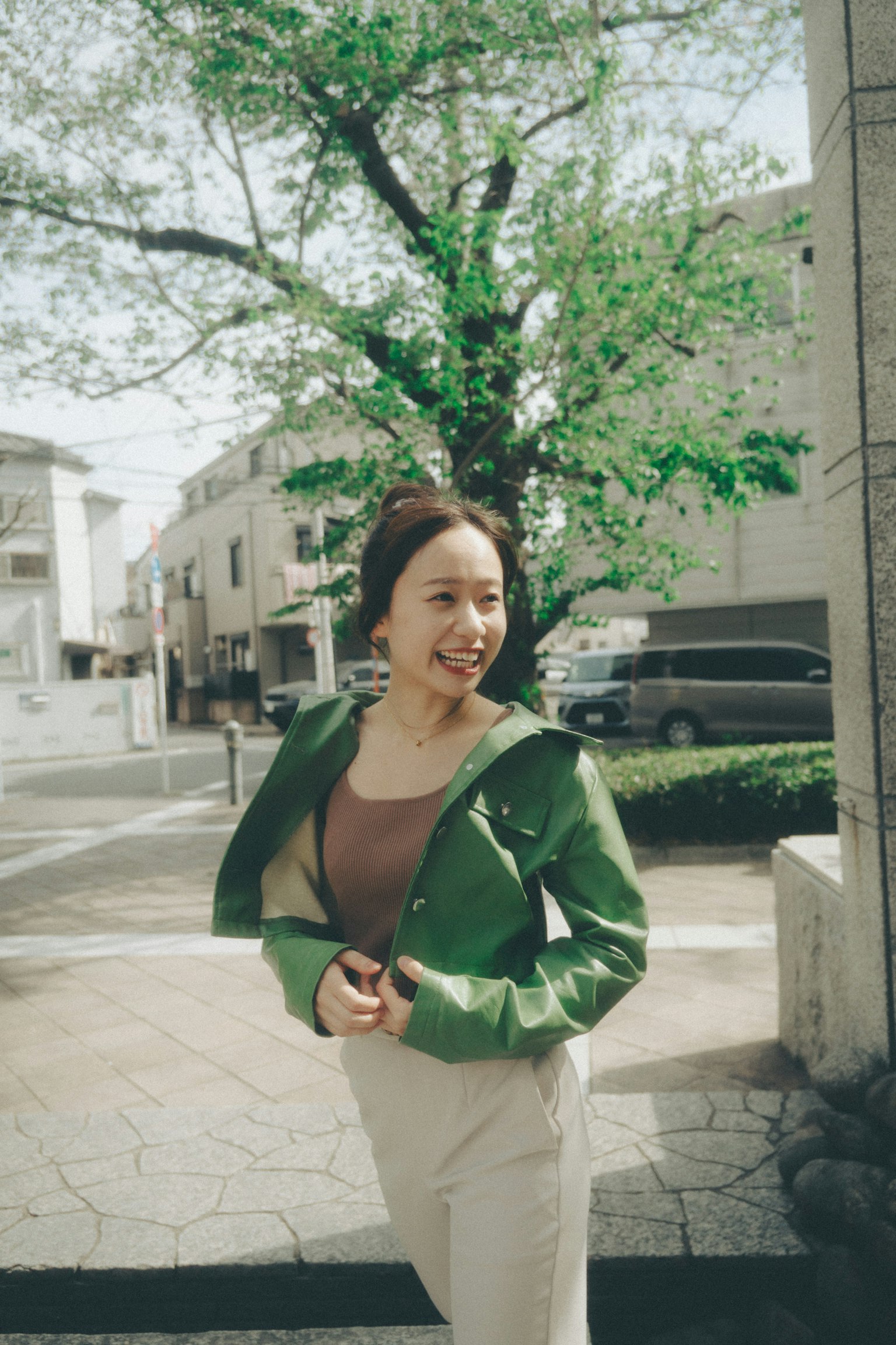 穿著綠色夾克的女性在街角微笑