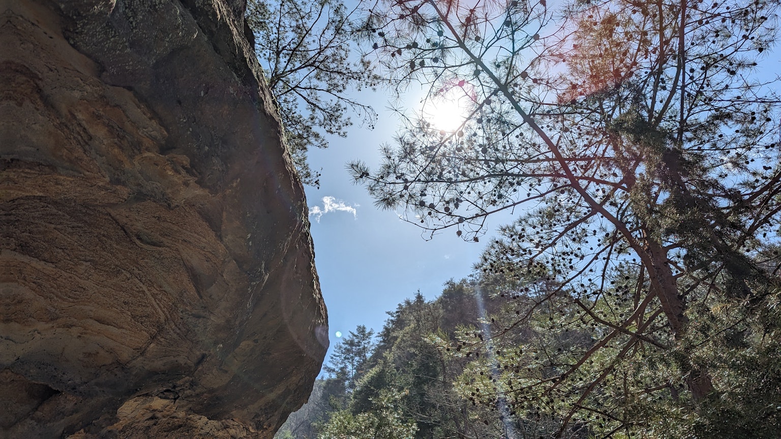 Vista de una gran roca y árboles bajo un cielo azul