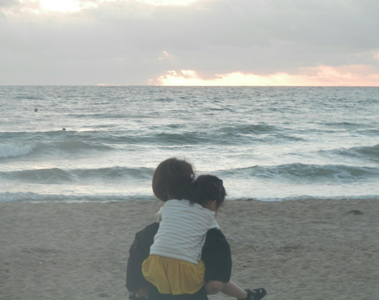 Silhouette d'un parent portant un enfant sur la plage coucher de soleil serein sur l'océan