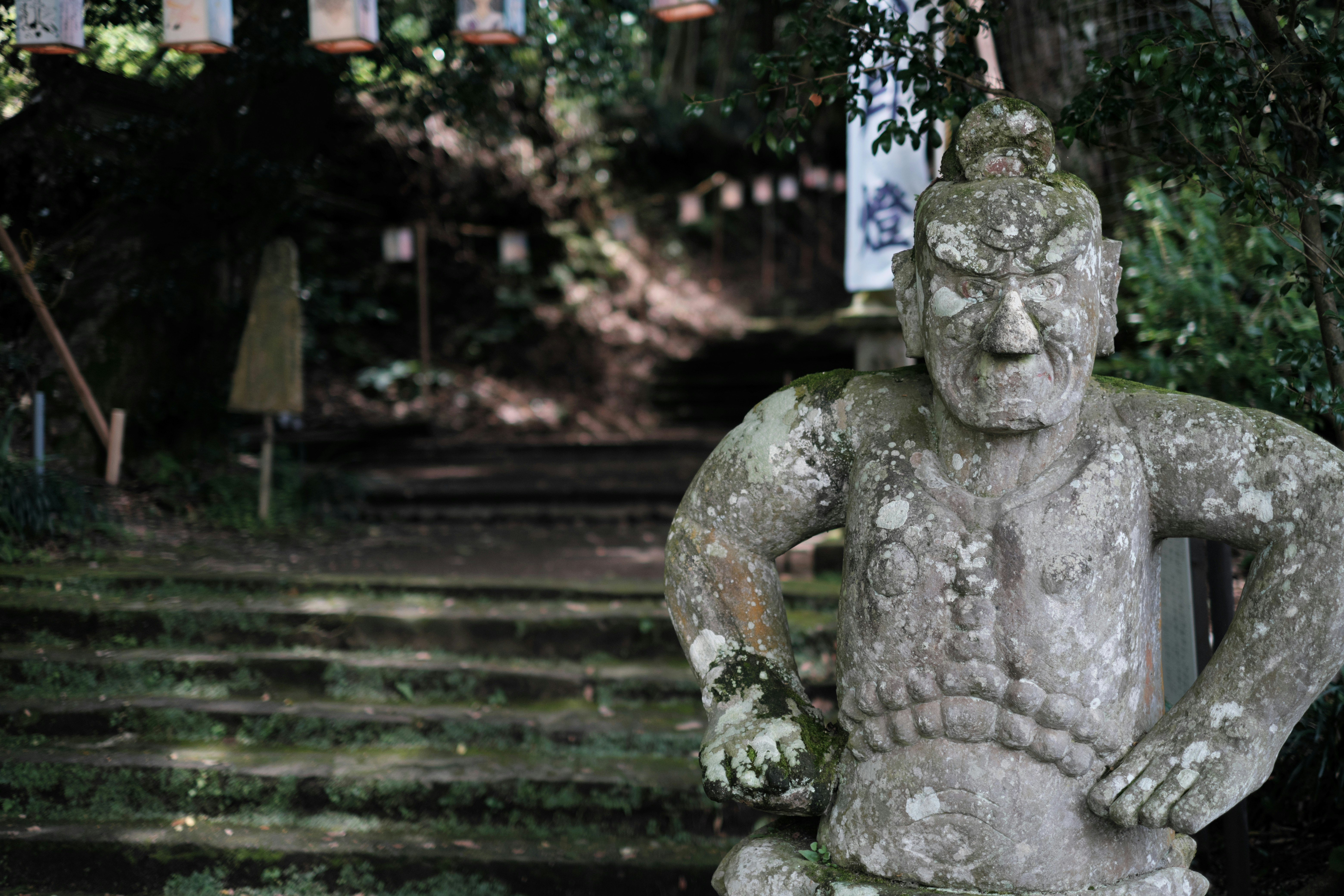 statue en pierre couverte de mousse près d’escaliers de jardin