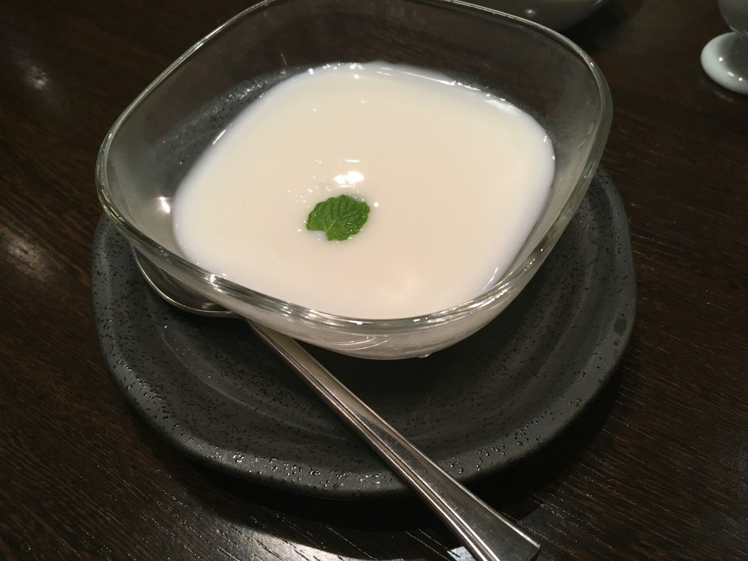 Puding krim dalam mangkuk persegi dengan hiasan daun mint