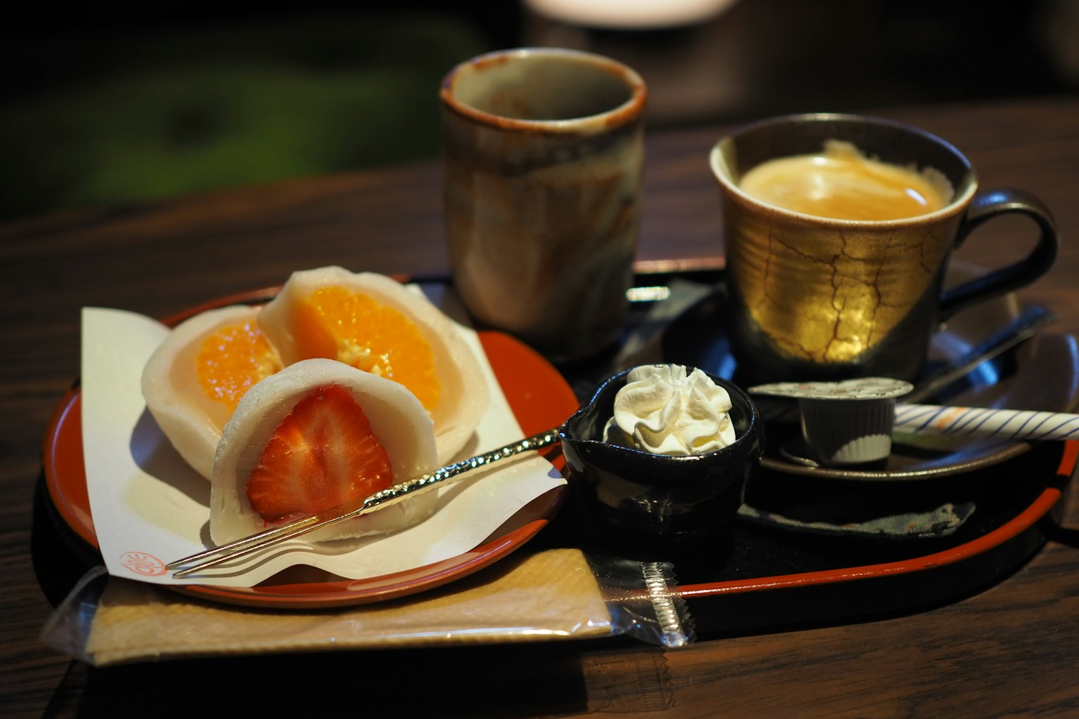 ชุดขนมญี่ปุ่นที่มีไส้ส้มและกาแฟเสิร์ฟในถ้วยตกแต่งและจานเล็กๆ ใส่ครีม