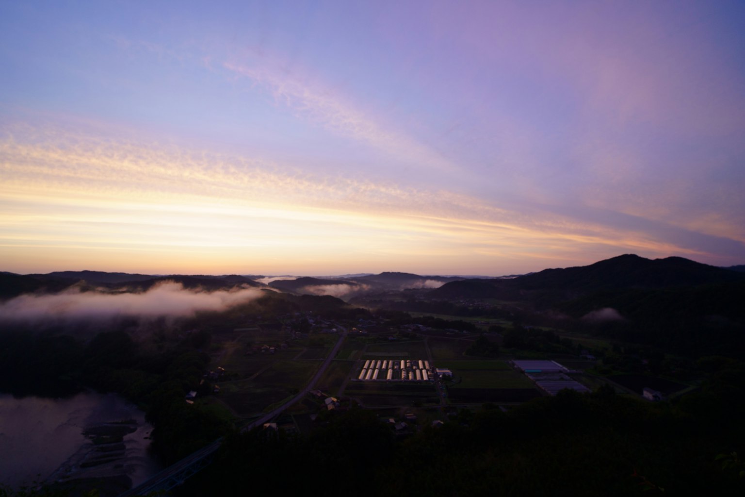 风景如画的日落，雾蒙蒙的山脉和田野