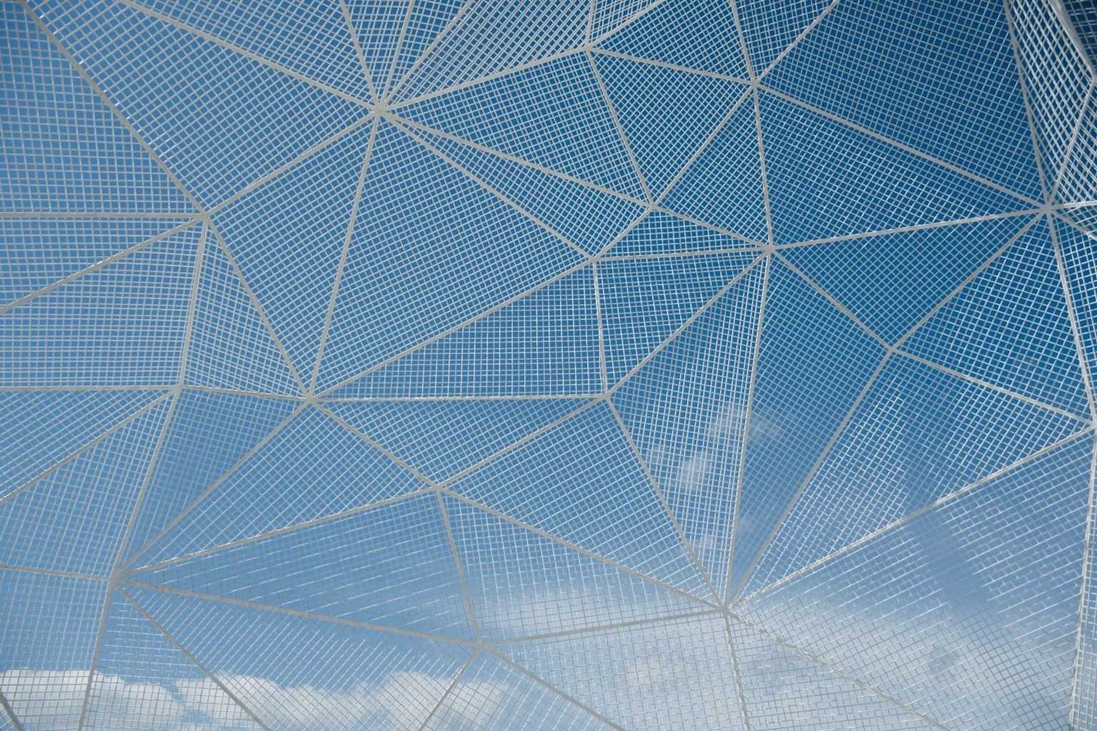 Structure en maille blanche contre un ciel bleu avec des nuages