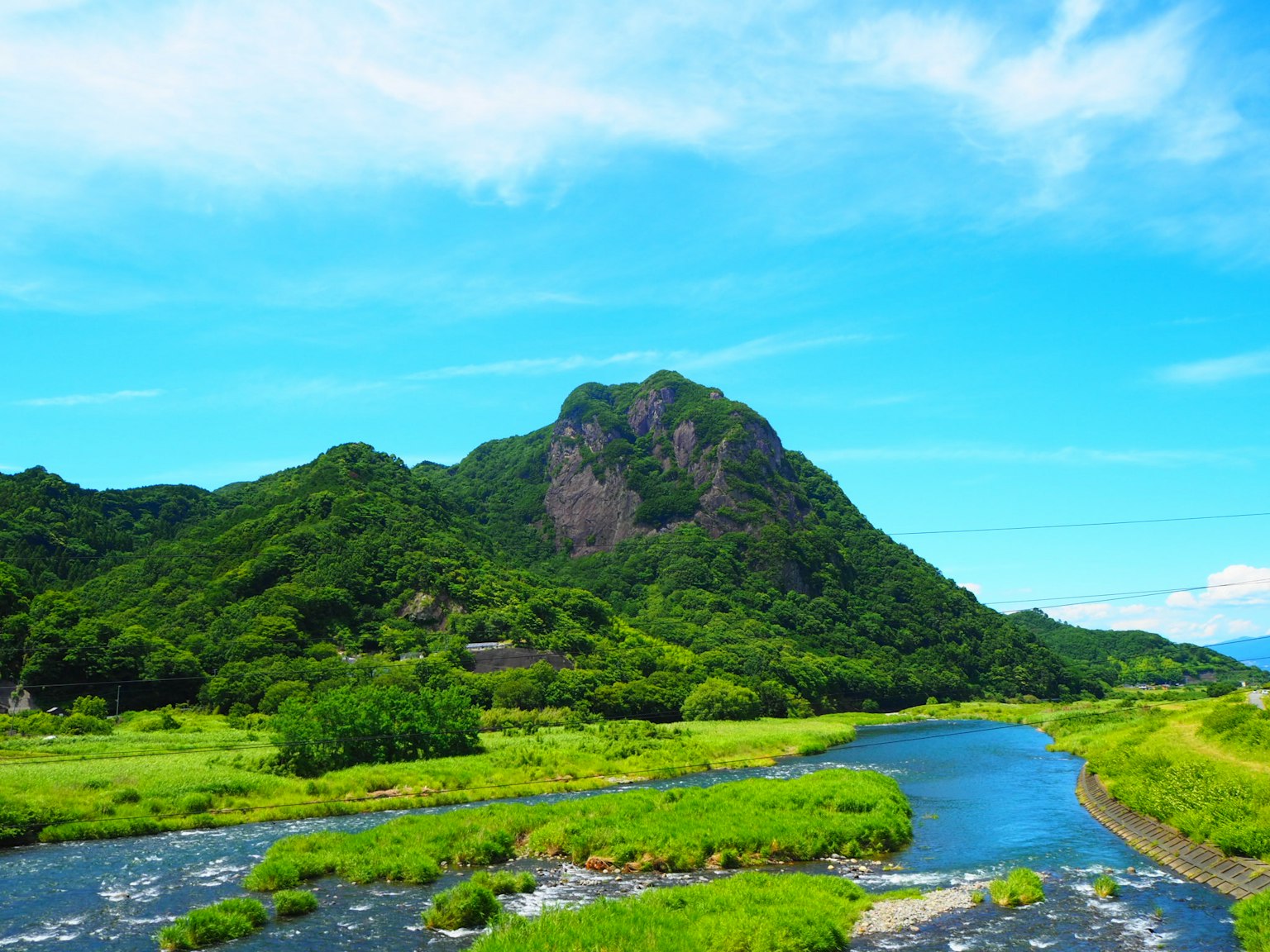 Pemandangan indah pegunungan hijau dan sungai di bawah langit biru