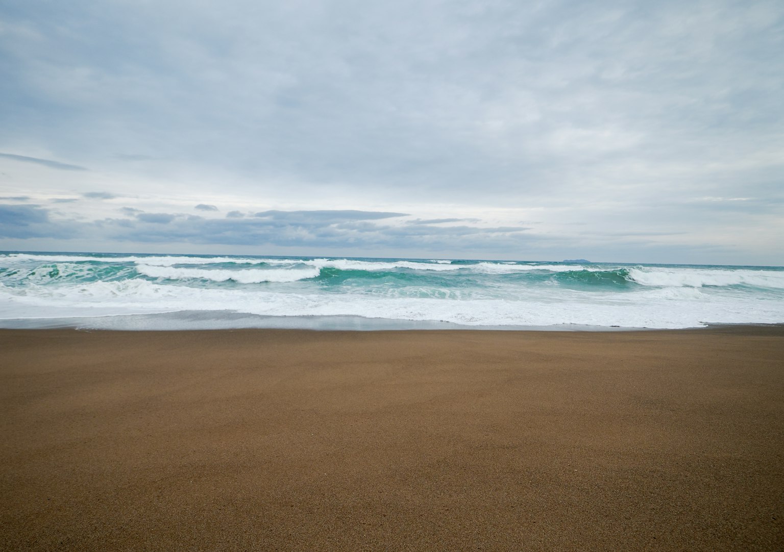 海浪在沙灘上拍打，天空陰雲密佈