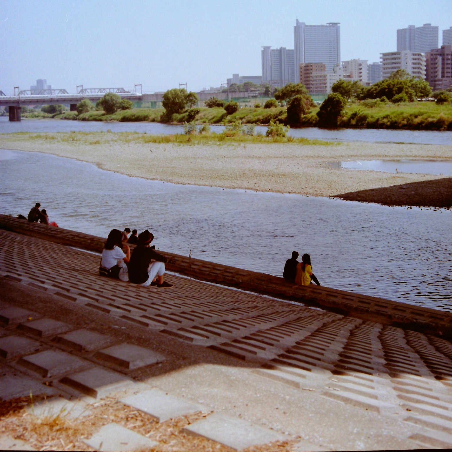 Personnes assises sur un pavé en pierre au bord de la rivière avec la ville en arrière-plan