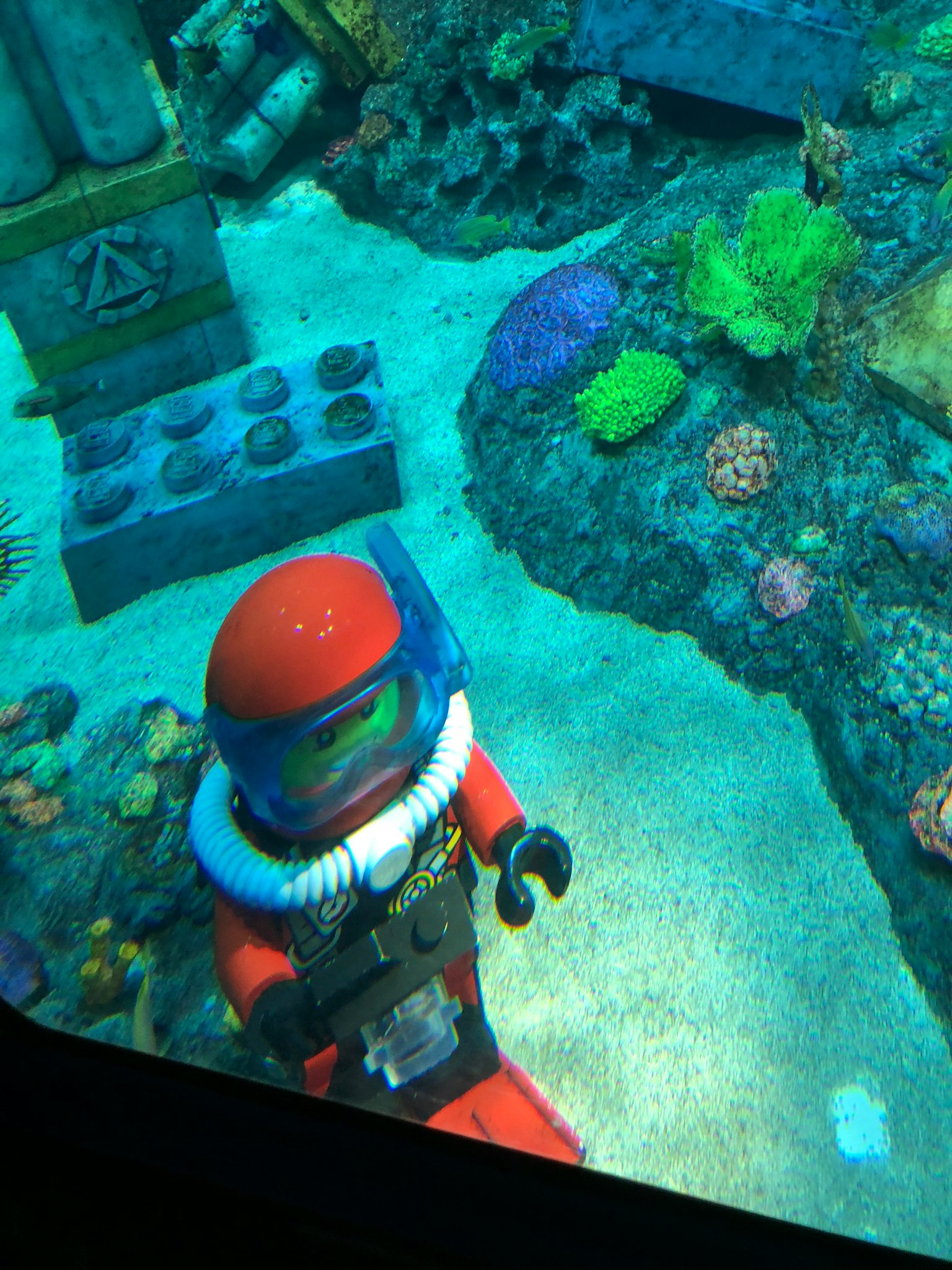 Un plongeur LEGO nageant parmi des coraux colorés sous l'eau
