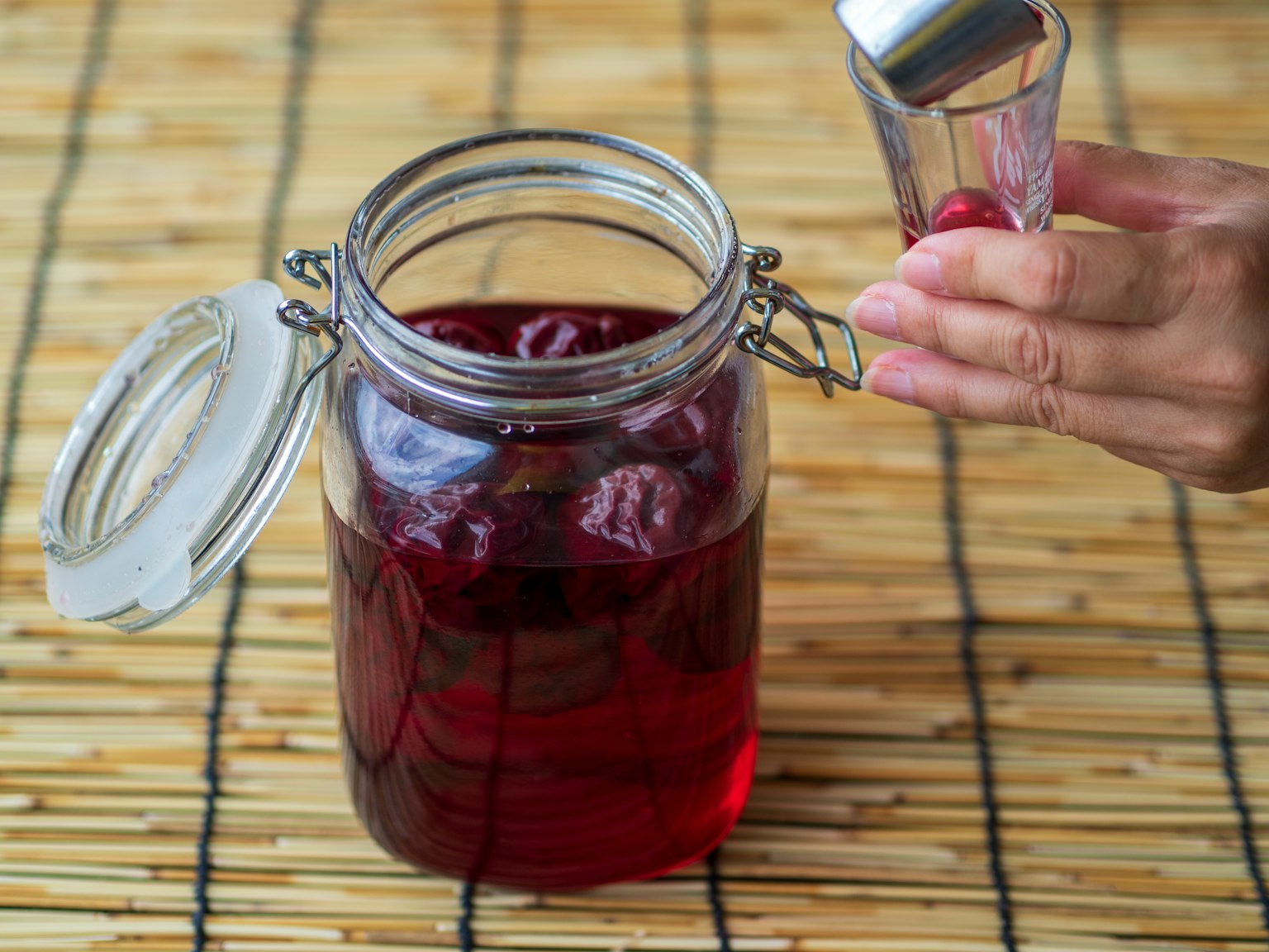 A hand reaching for a jar filled with red jam