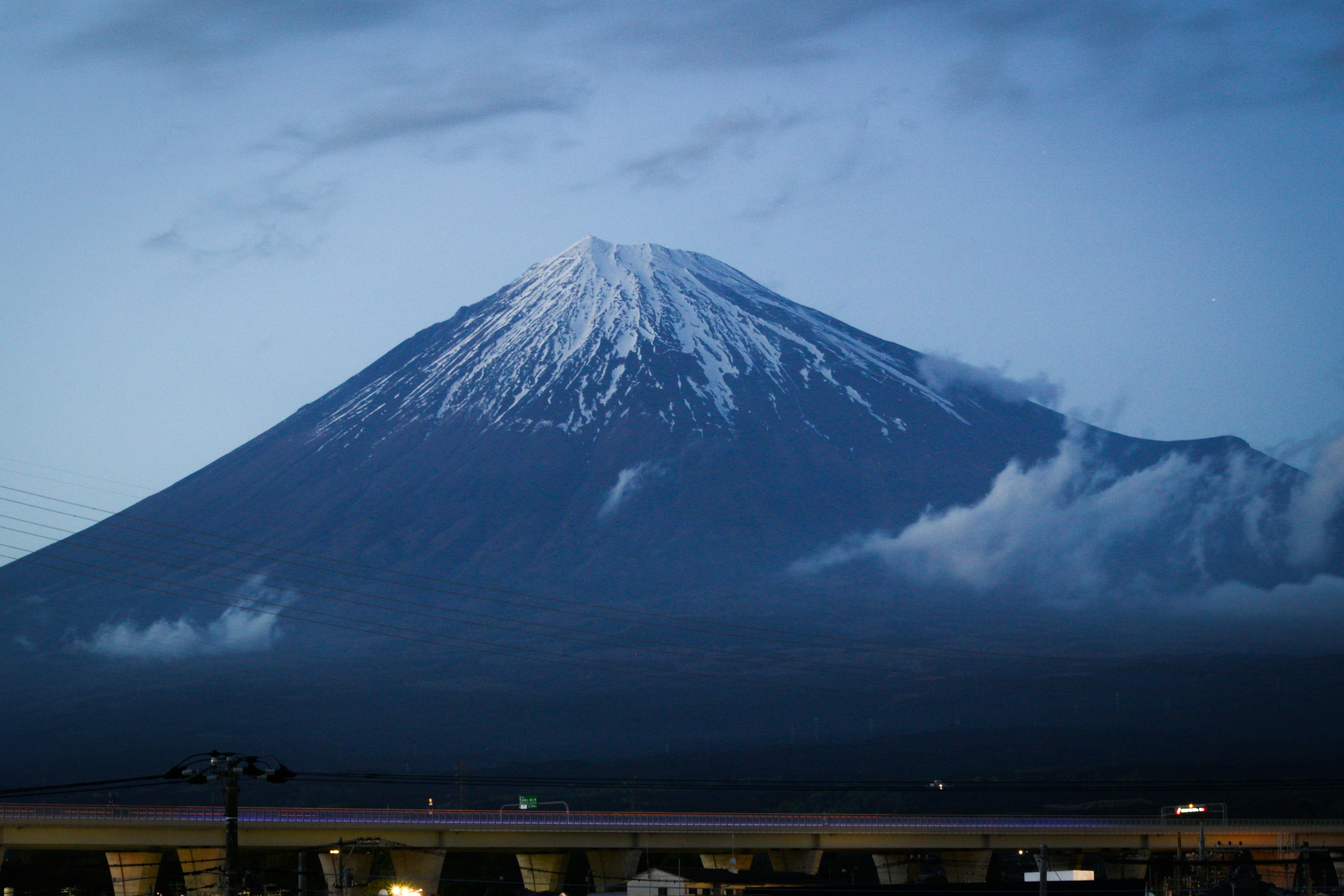 夜の雪雲に包まれた富士山と駅のホームの灯り