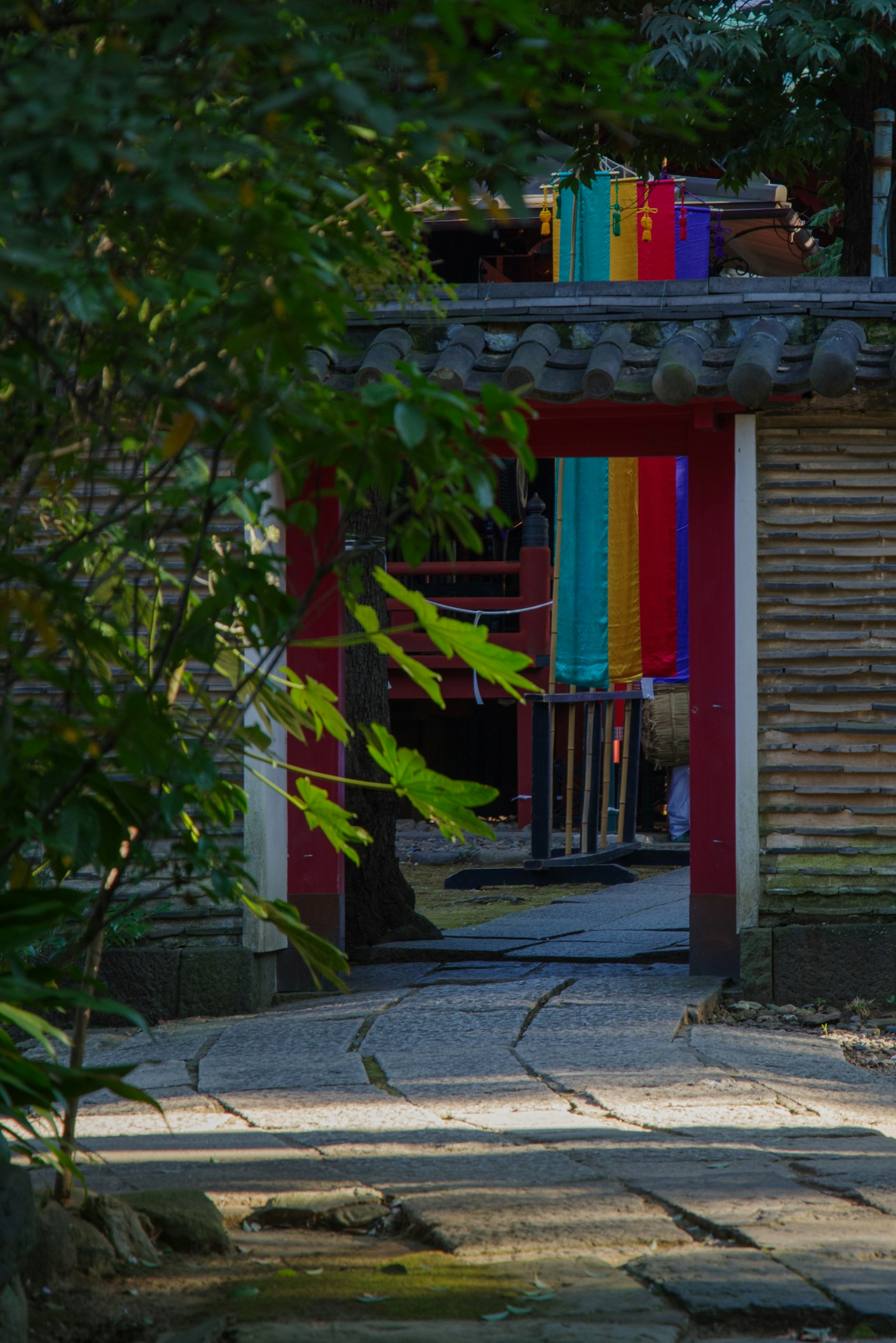 A vibrant view of a red gate surrounded by greenery with colorful fabric hanging