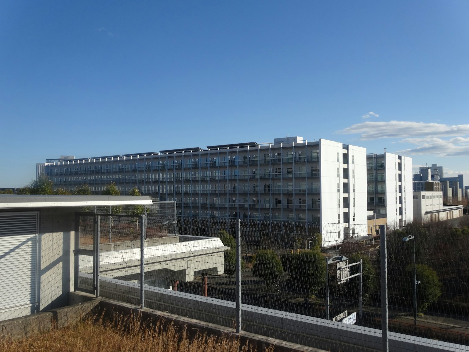 Modern building exterior under blue sky with nearby low-rise structure
