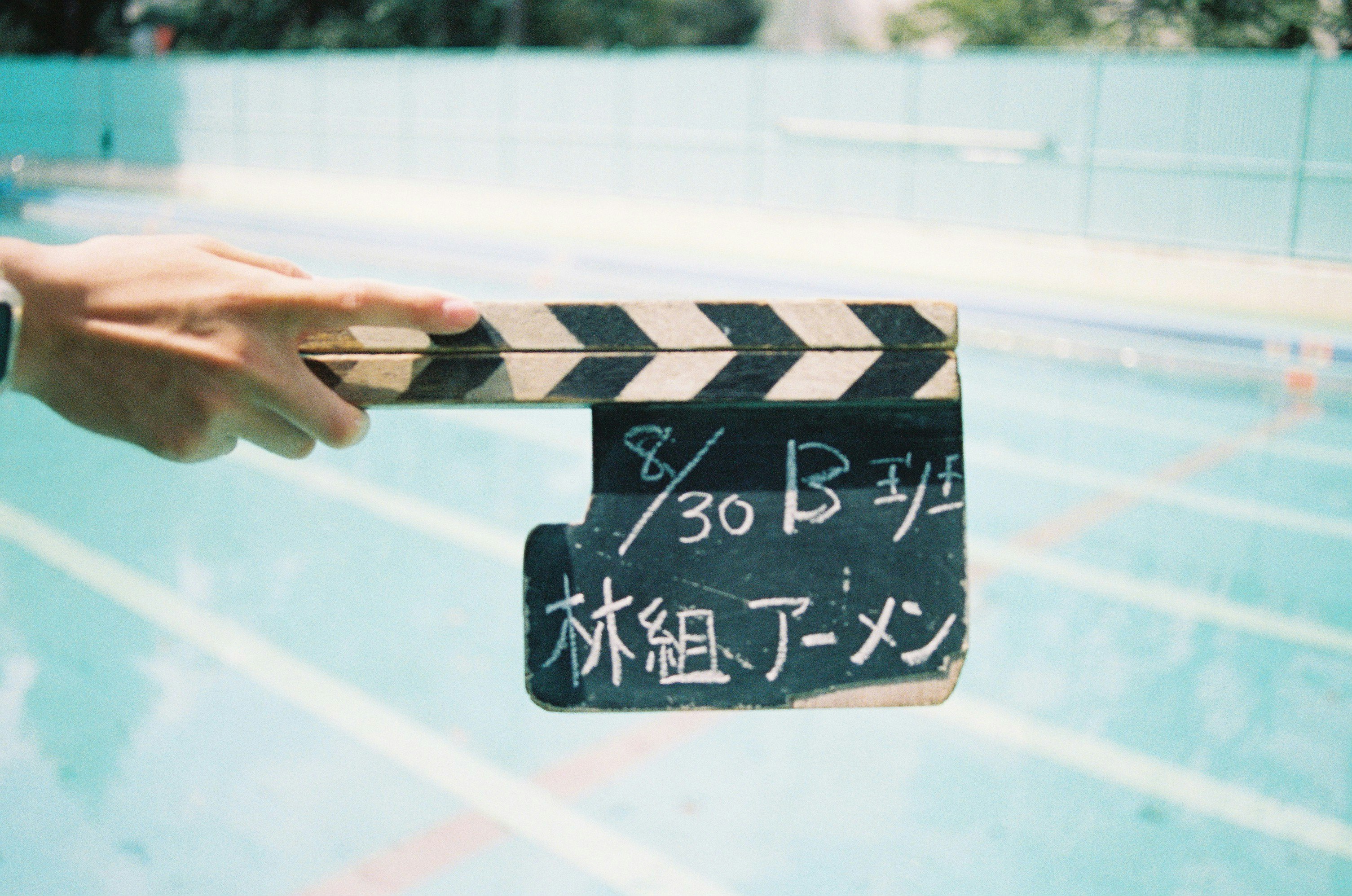プールサイドの手と黒板風の掲示板