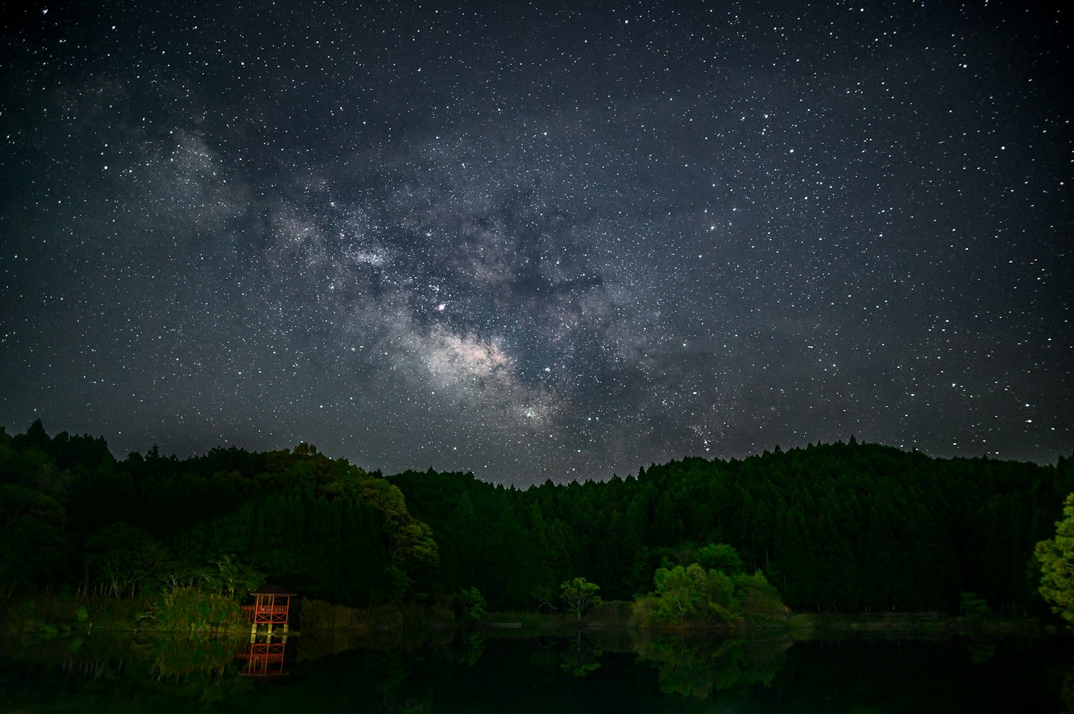 Cielo nocturno lleno de estrellas y la Vía Láctea Estructura roja junto al lago