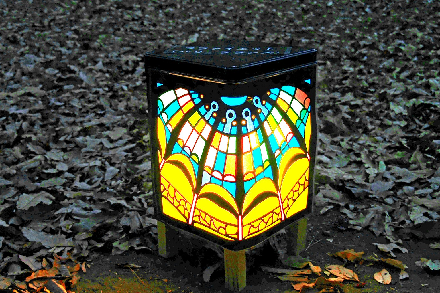 Colorful stained glass lamp placed on fallen leaves in a park