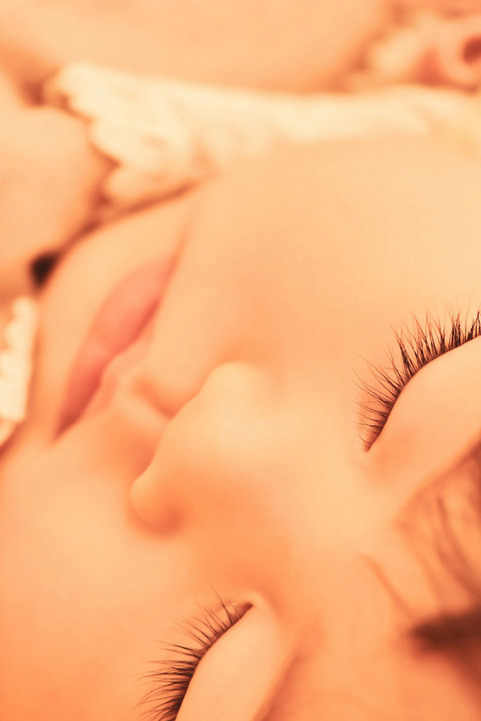 赤ちゃんの顔が穏やかに眠っている様子 ふわふわの毛と長いまつげが特徴