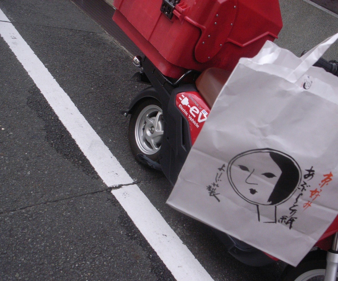 Scooter rojo junto a una bolsa de papel en un paso de peatones