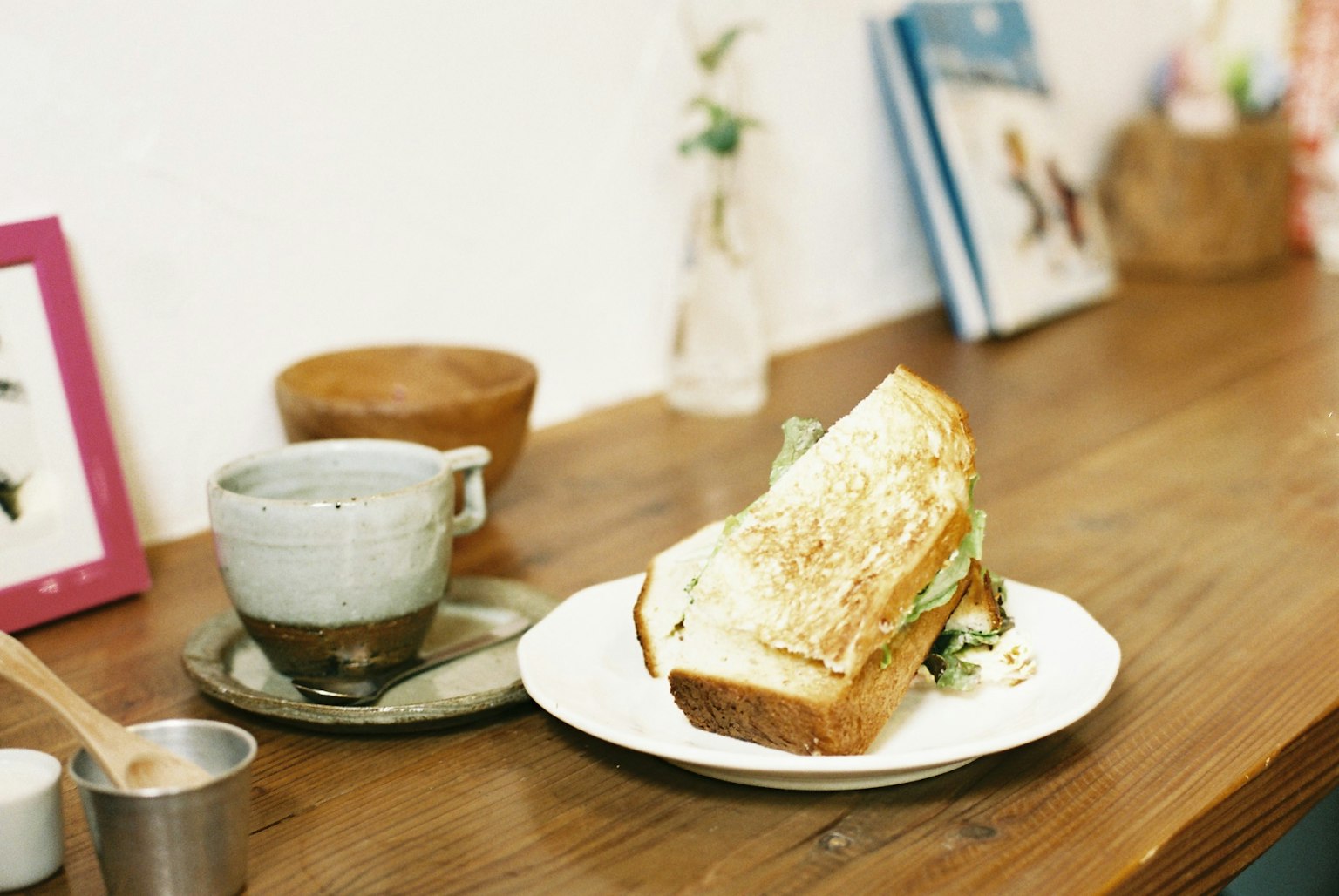 Un sandwich sur une assiette à côté d'une tasse de café sur une table en bois