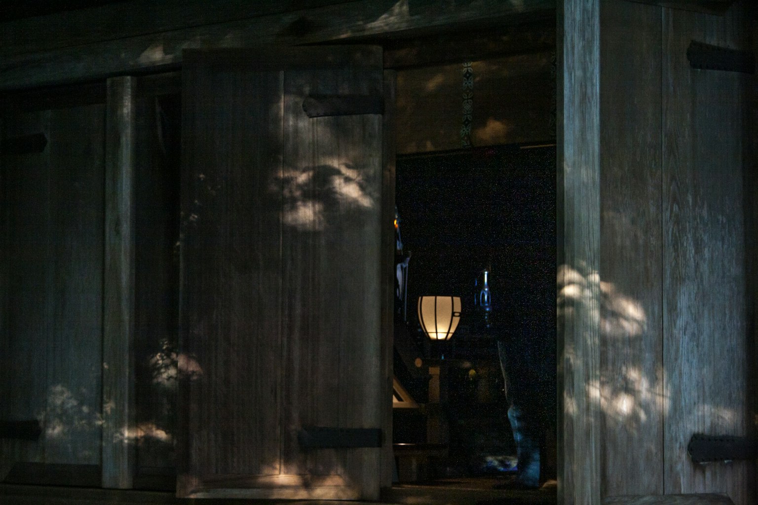 Pintu kayu terbuka yang mengungkapkan interior yang diterangi lembut dengan refleksi cahaya