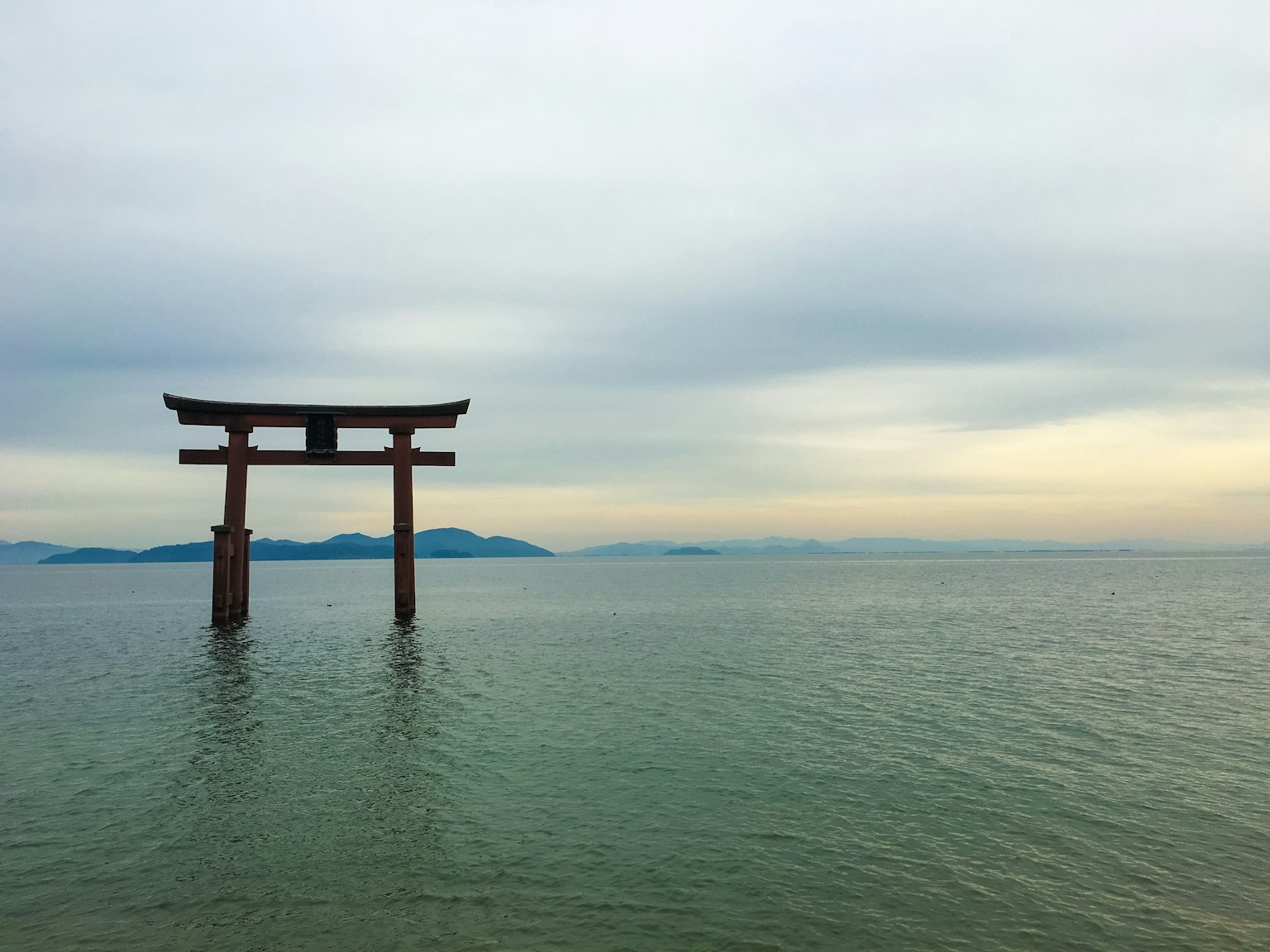 Torii gate standing in calm water with a serene sky