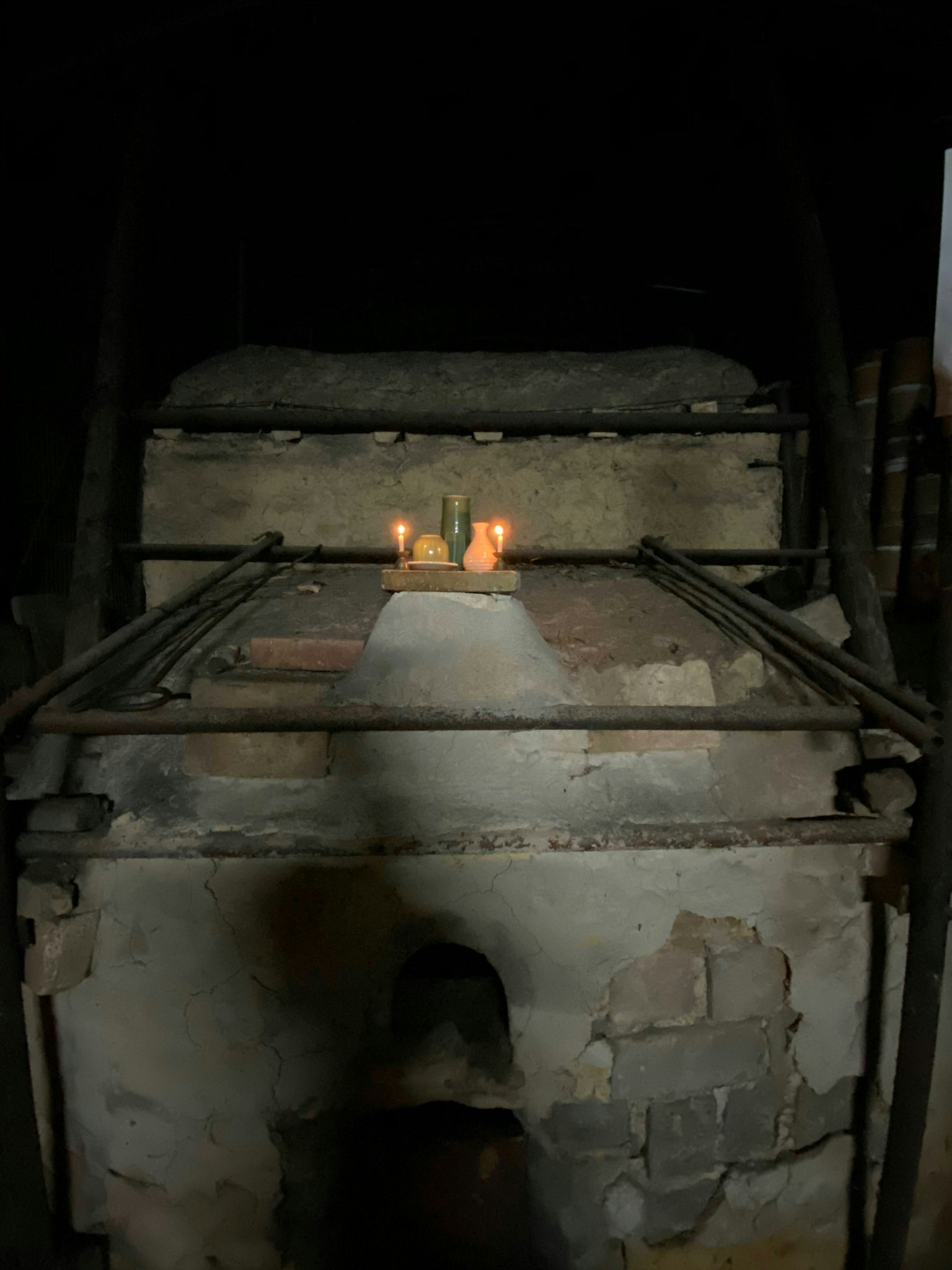 A quiet scene in a dark room with a lit fire in front of an old furnace