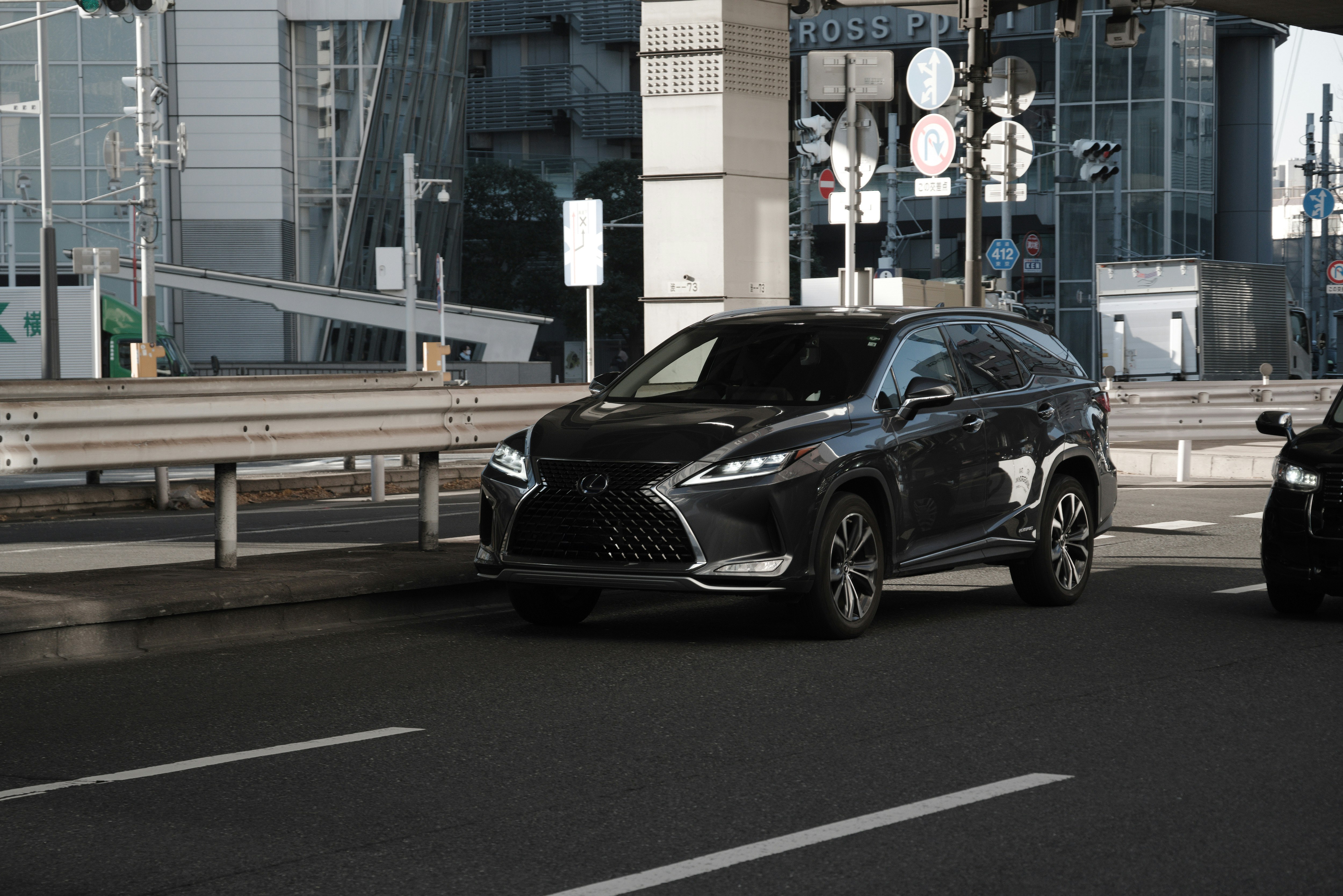 vista frontale di una Lexus nera che guida su una strada cittadina