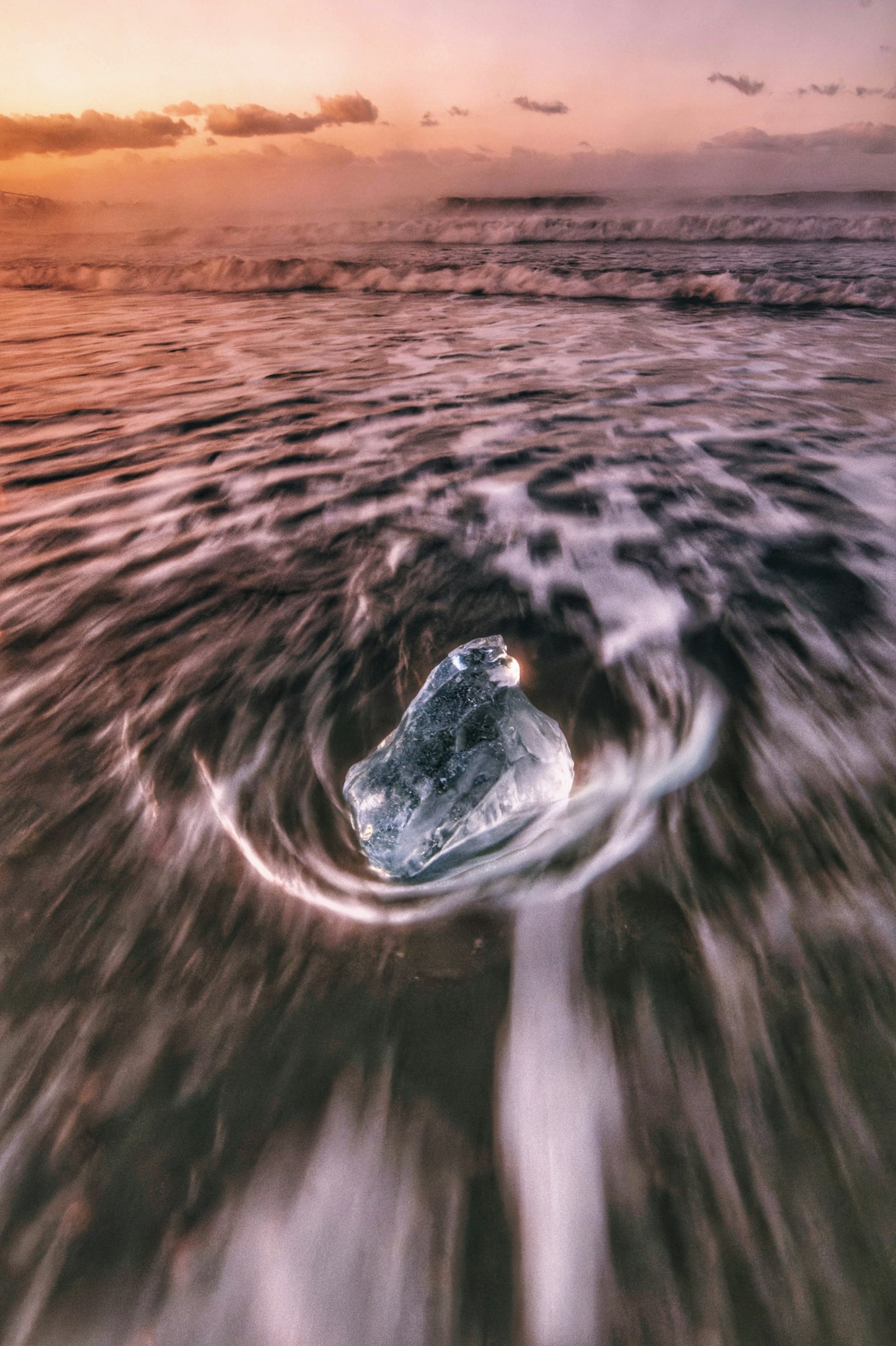Ein transparenter Eisblock, der in den Wellen des Ozeans schwimmt, mit einem schönen Sonnenuntergang im Hintergrund