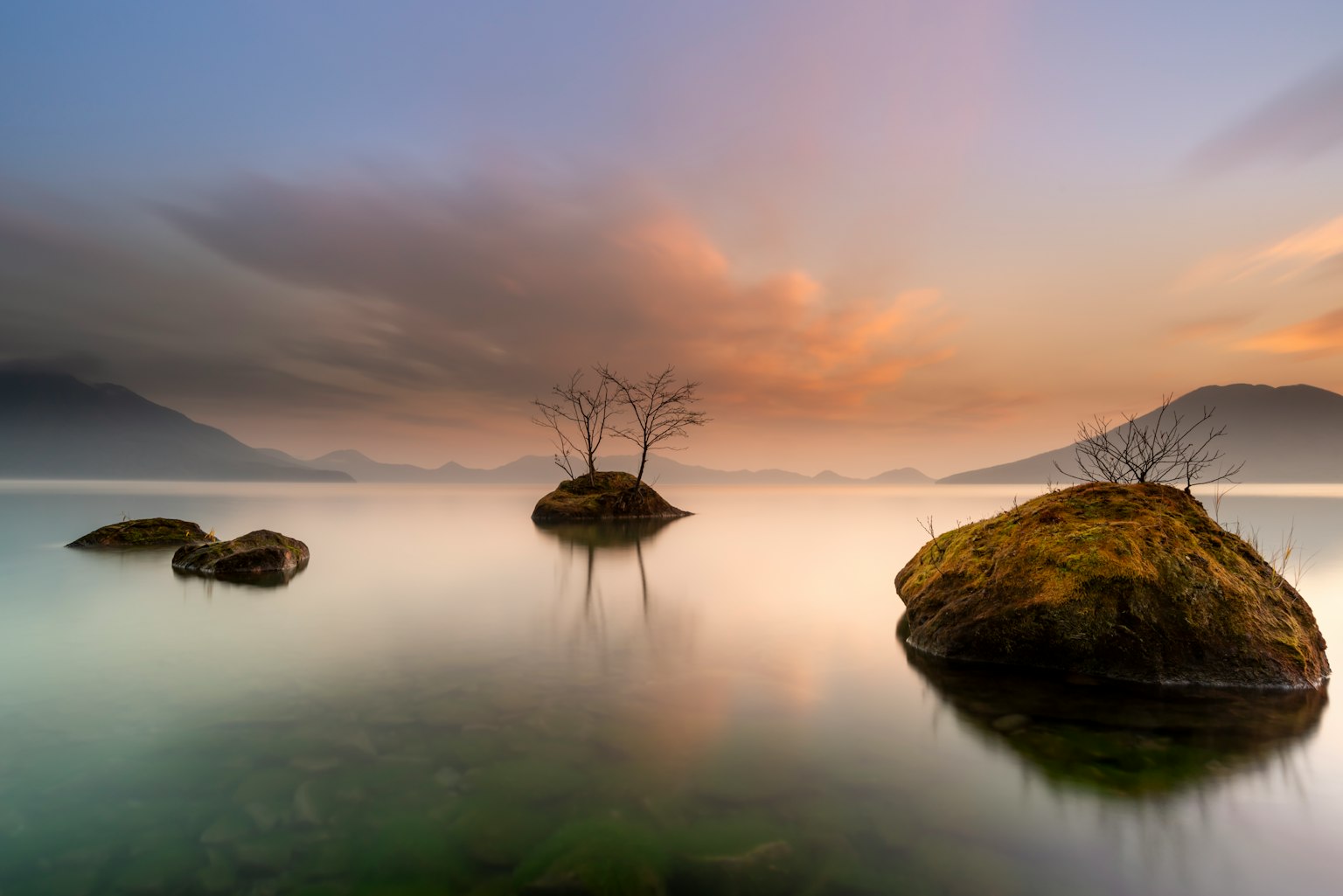 Silhouette di rocce e alberi su un lago sereno cielo al tramonto bellissimo