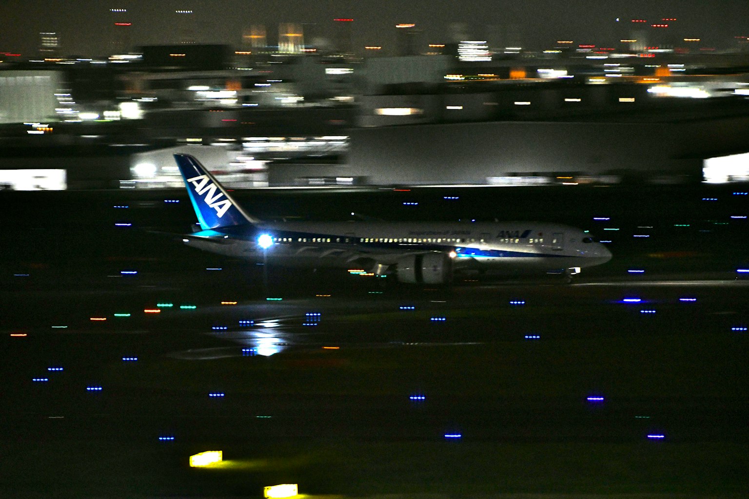Avion ANA atterrissant la nuit dans un aéroport