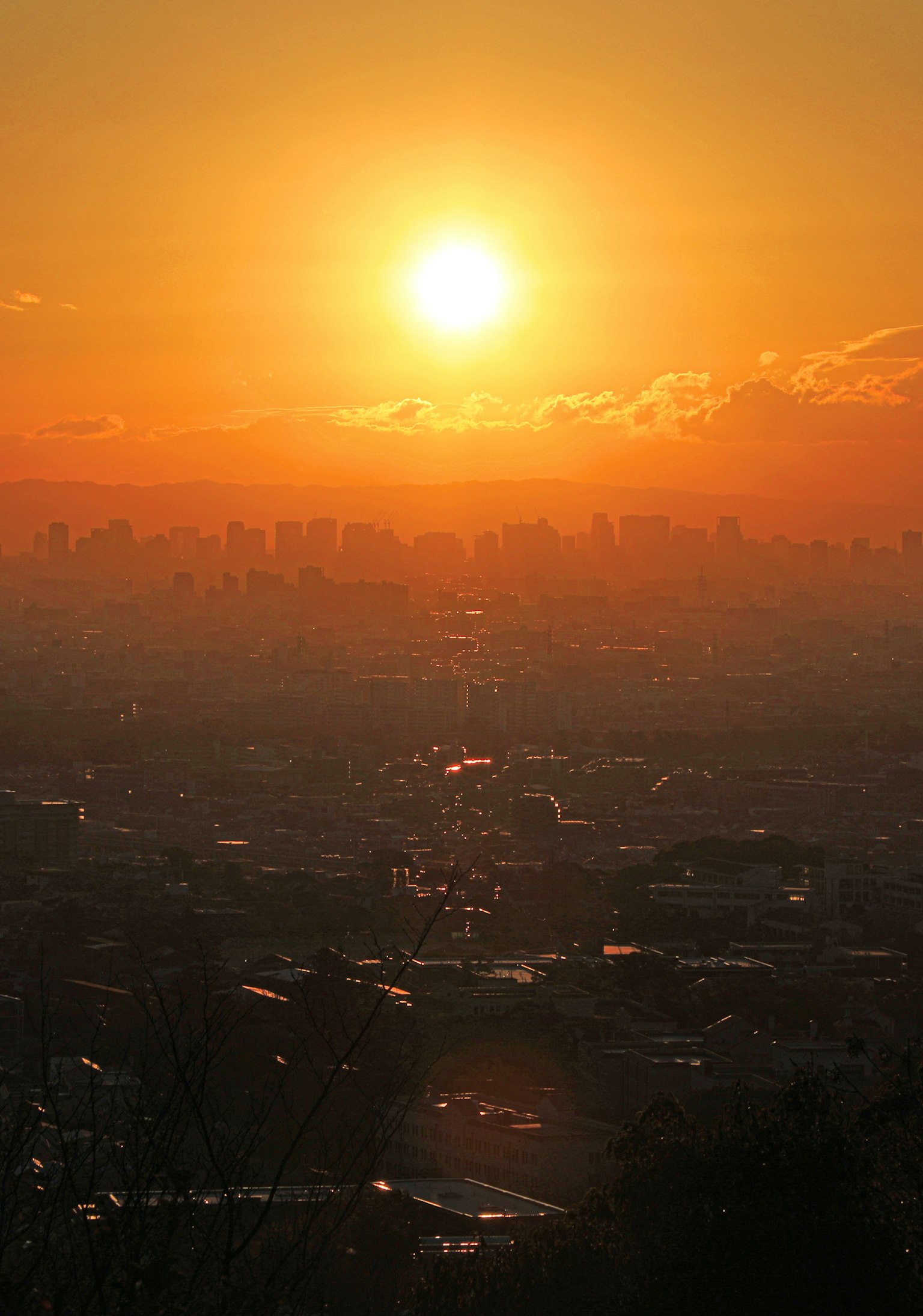Schöne Landschaft mit der Sonne, die über der Silhouette einer Stadt untergeht