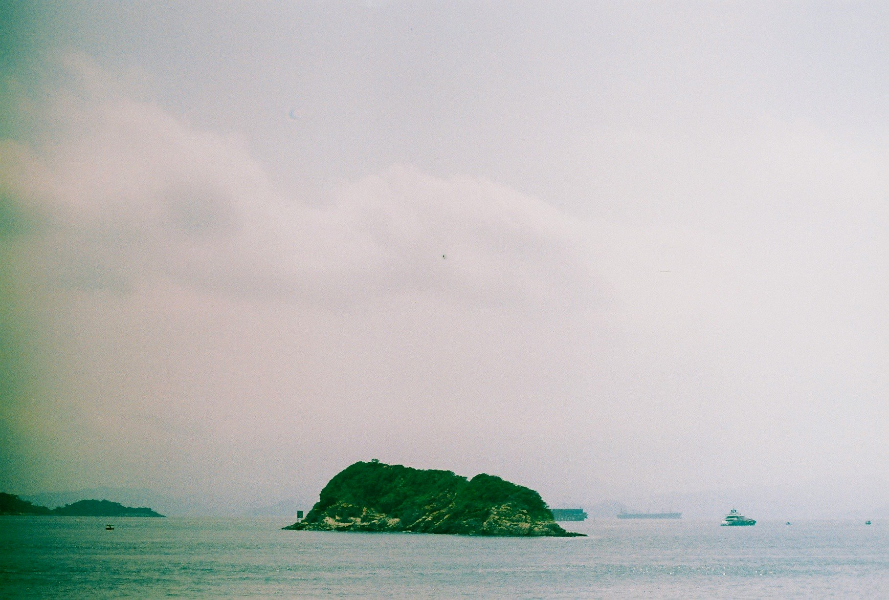 霧のかかった海辺に浮かぶ小島と遠景の船