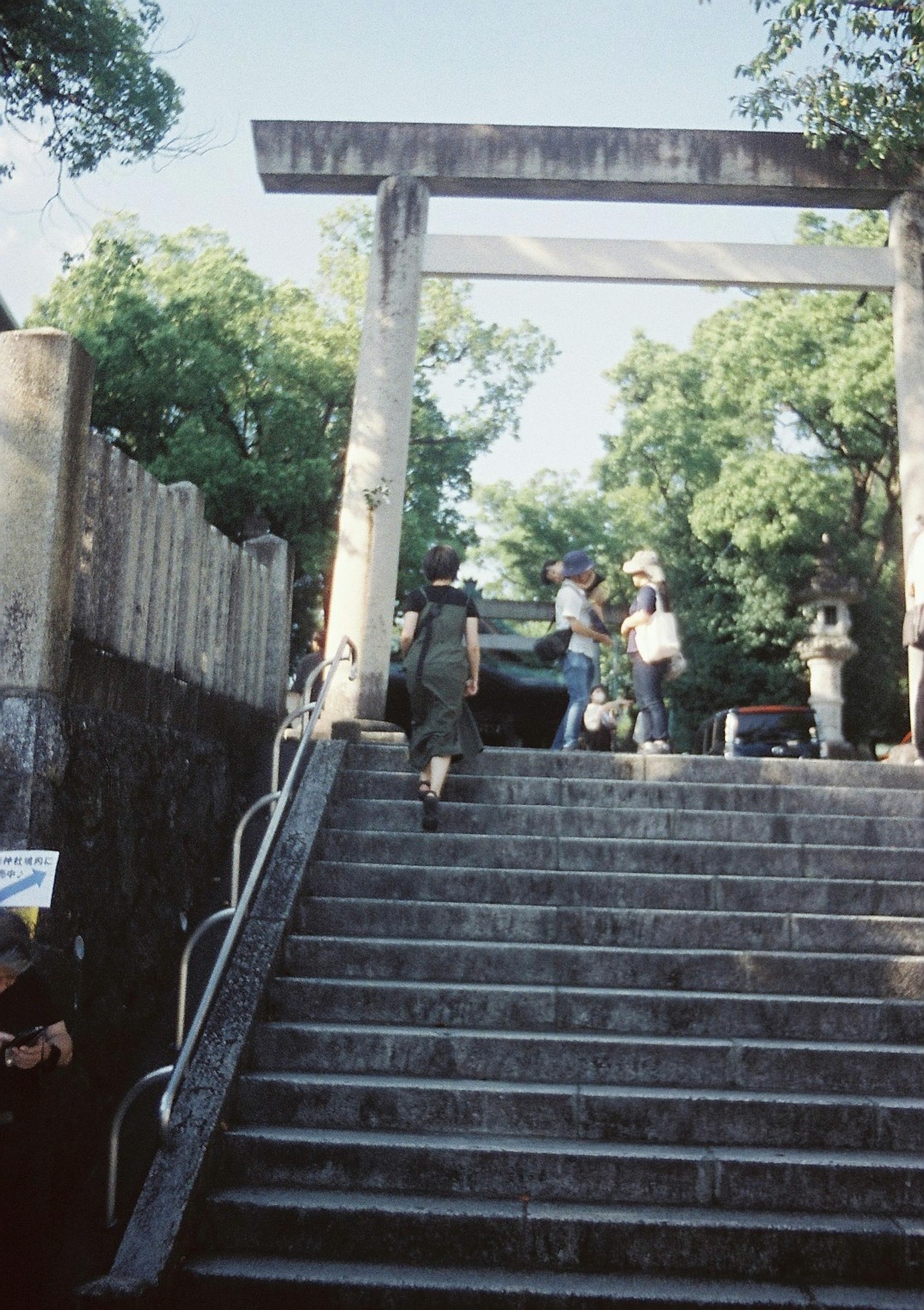 People ascending stairs with a torii gate in the background
