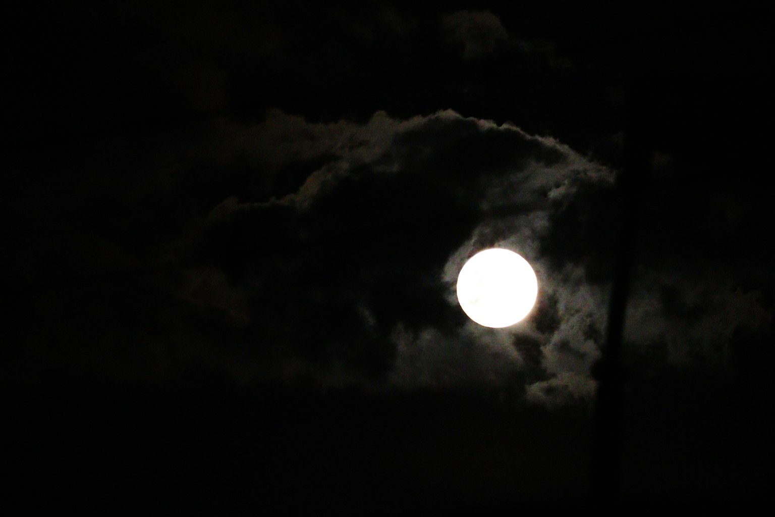 Bulan terang dikelilingi awan gelap di langit malam