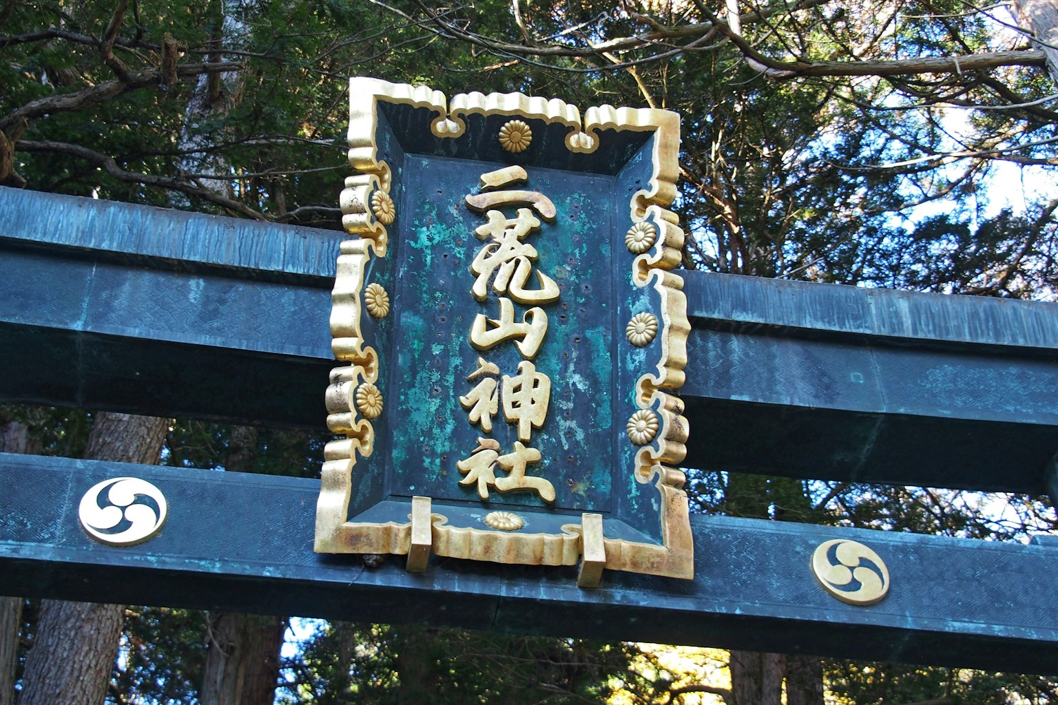 Puerta torii azul con un letrero de santuario en caracteres dorados