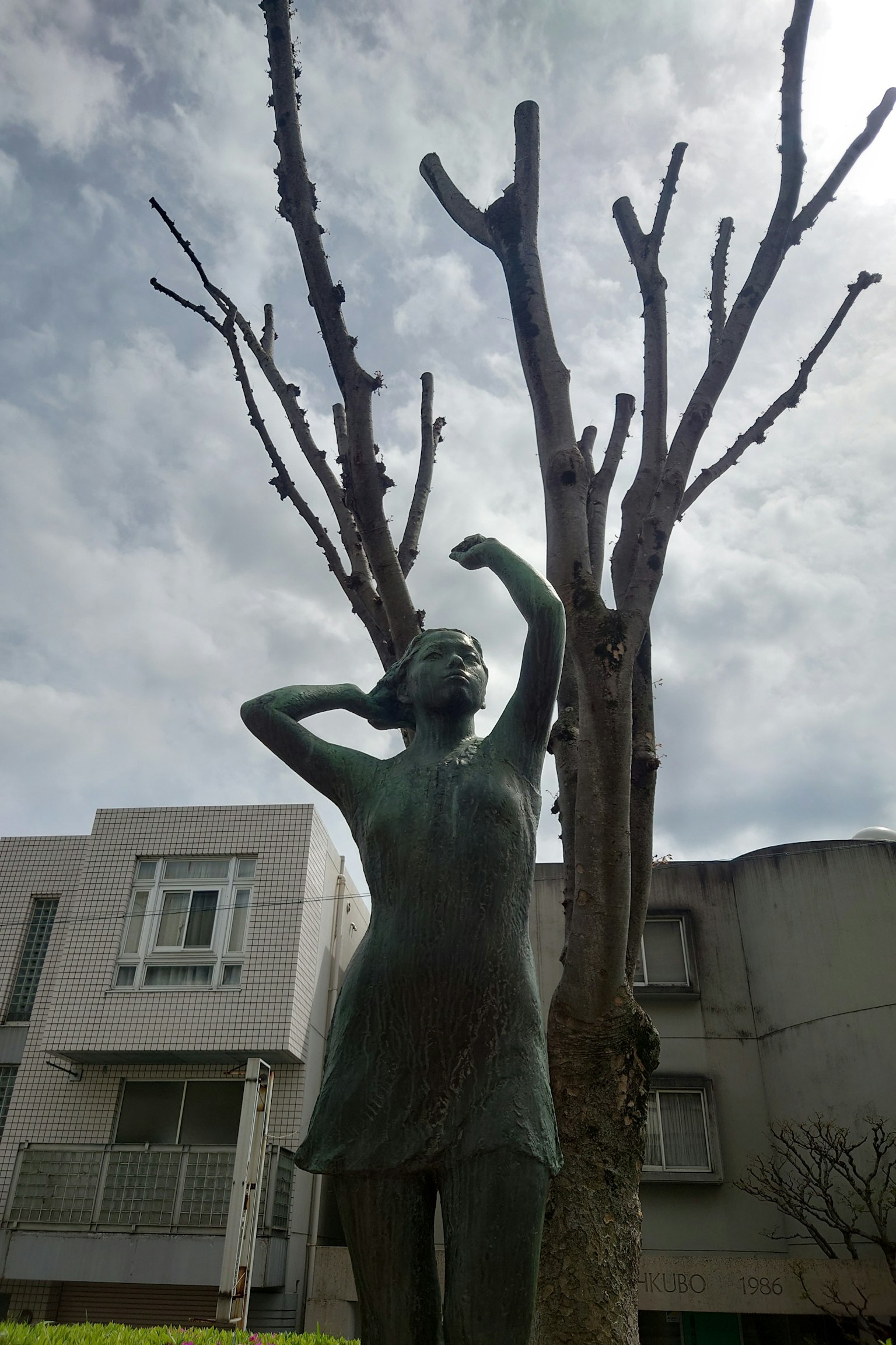 公园中的女性雕塑与枯树和灰色天空