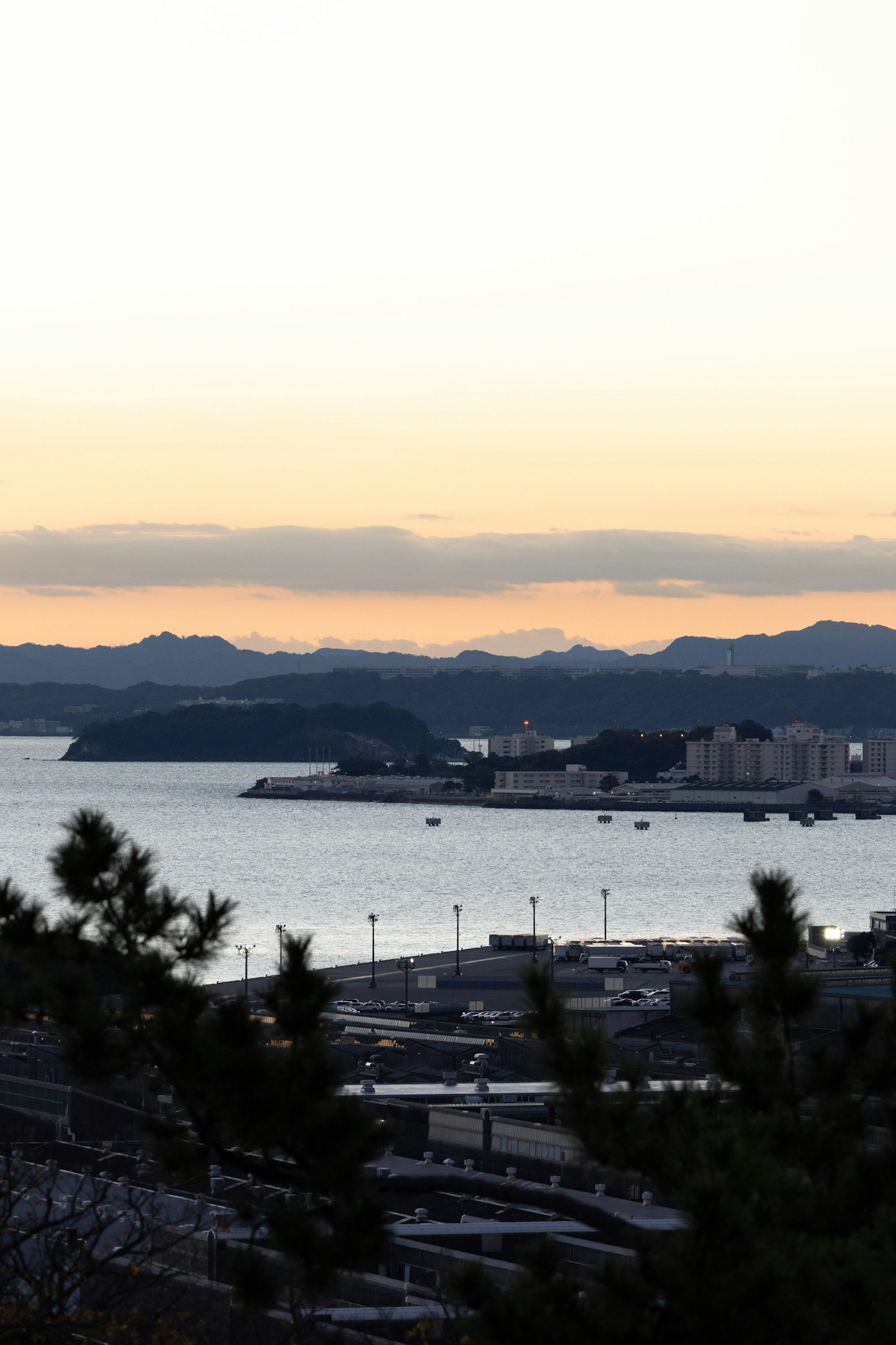 Cảnh biển và núi vào lúc hoàng hôn có cả cảng và tòa nhà