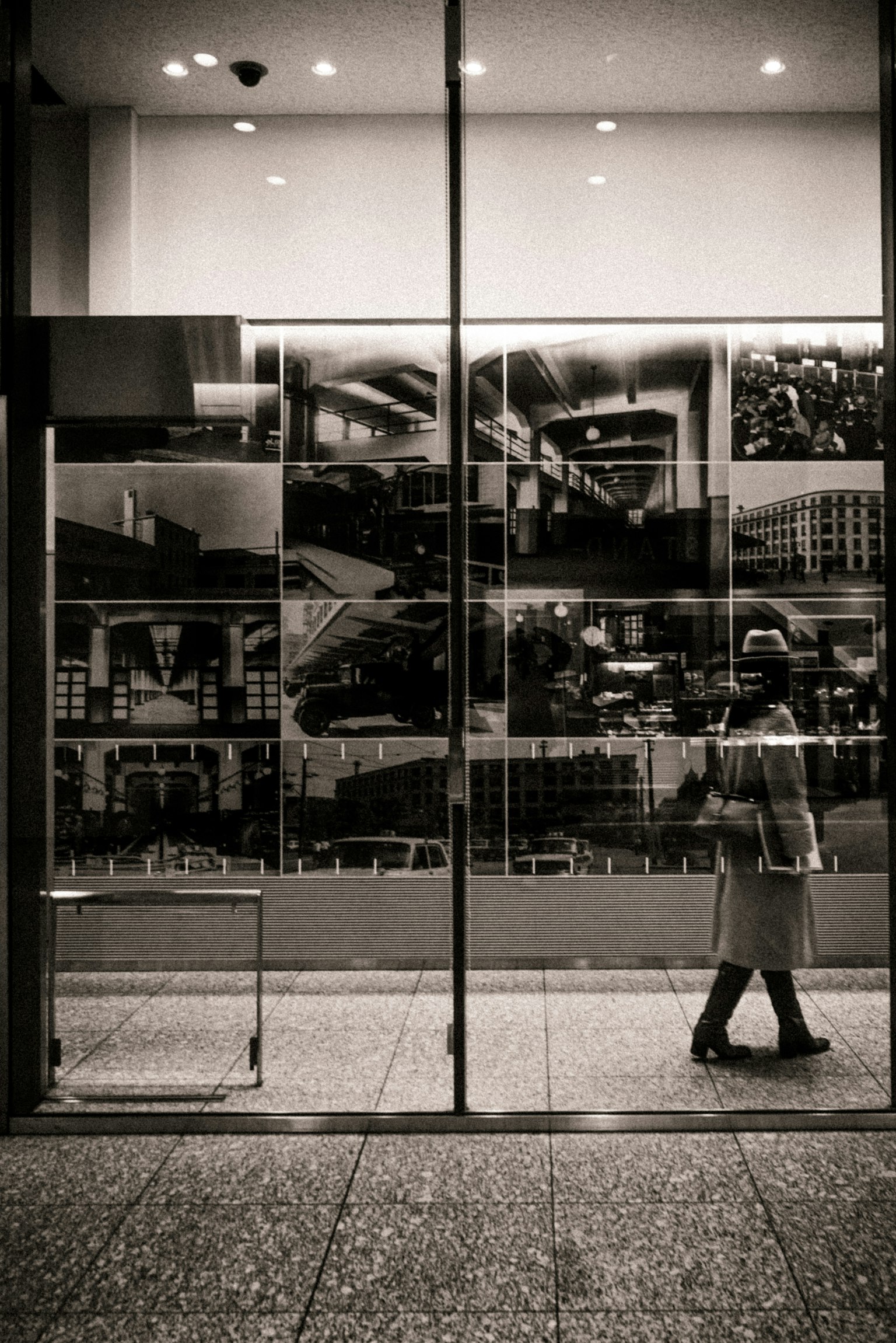 A woman walking in front of glass with black and white photographs