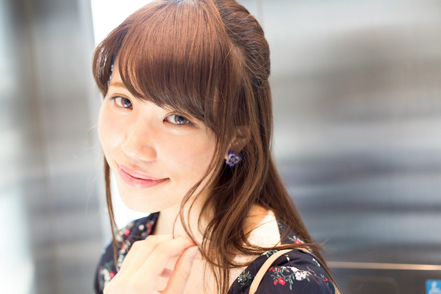 Retrato de una mujer sonriendo en un ascensor Cabello largo y suave de color marrón con atuendo floral