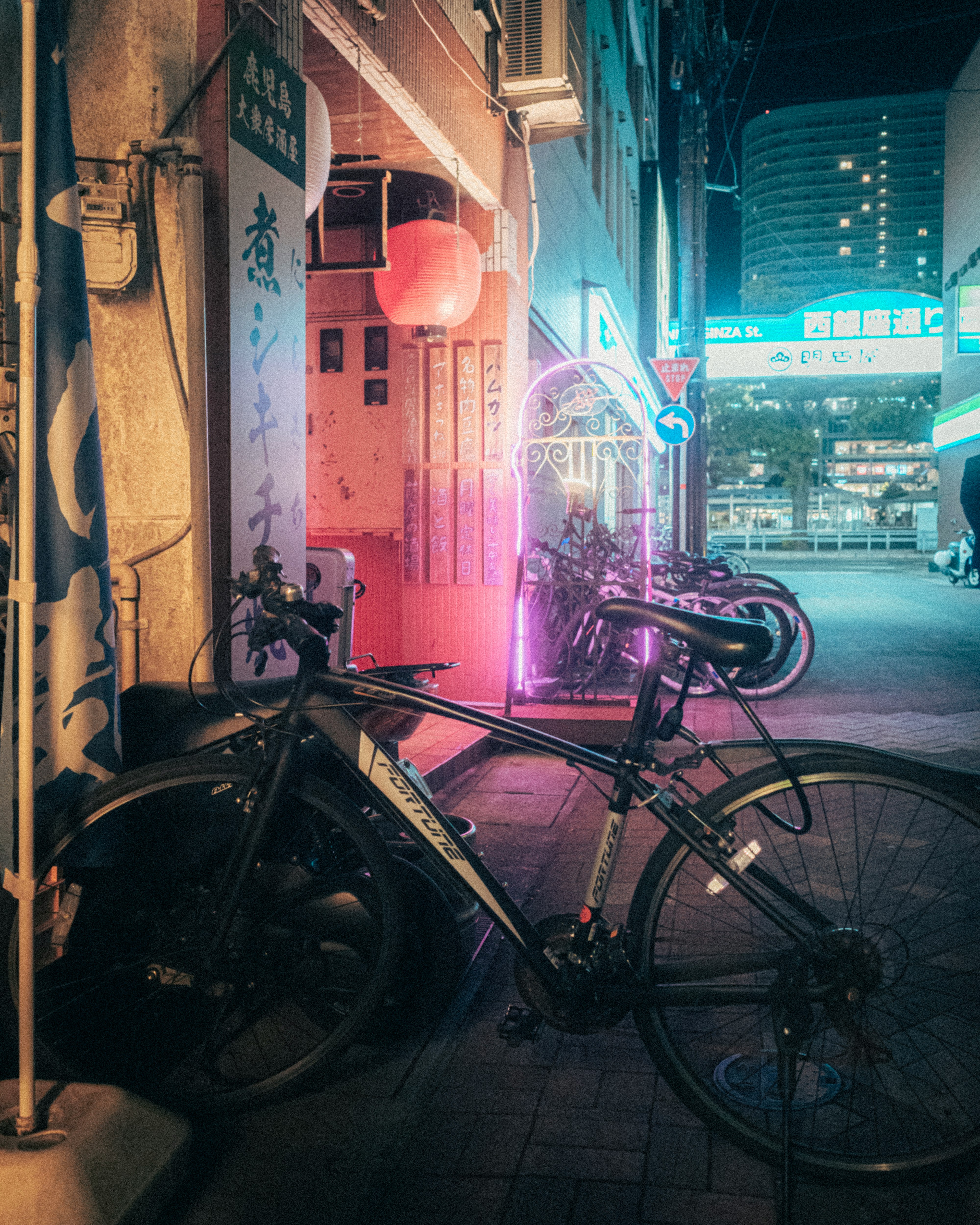 自転車が並ぶ夜の路地の看板とネオンの光
