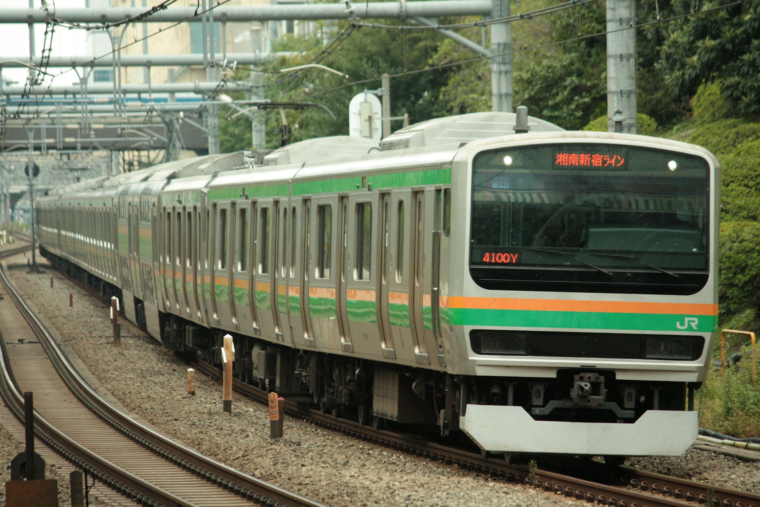 一列帶有綠色和橙色條紋的火車在軌道上行駛
