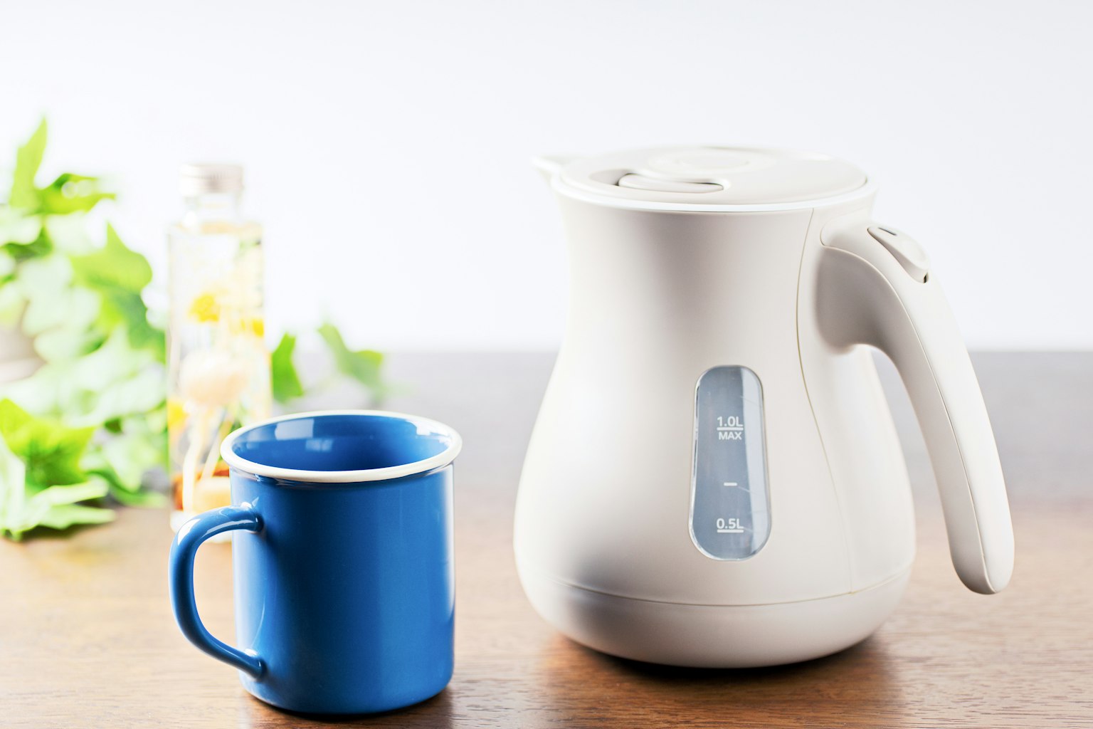 Una kettle elettrica bianca e una tazza blu sono posizionate su un tavolo di legno