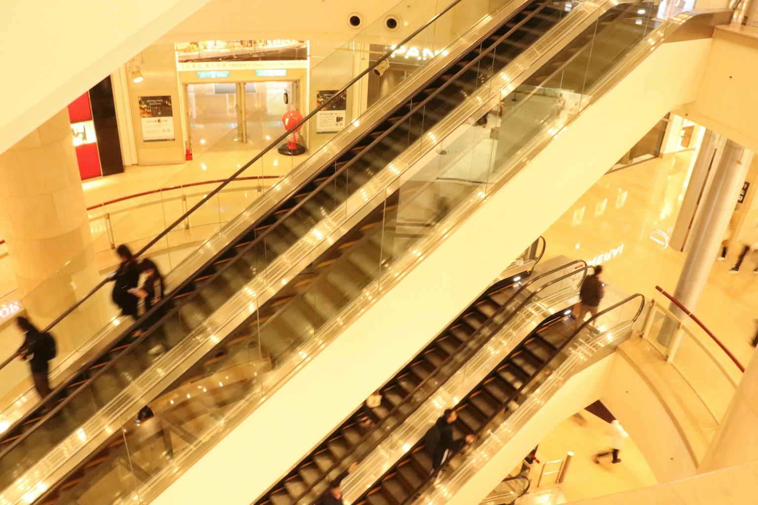 Vista de escaleras mecánicas en un centro comercial con personas moviéndose